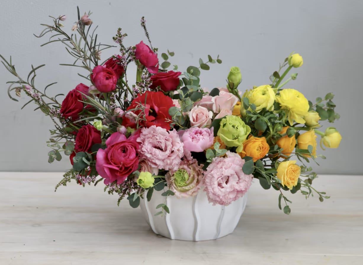 Rays of Sunshine - WeHo - This arrangement includes a mix of ranunculus, lisianthus, and spray roses in a white ceramic vase. Pinks and yellows!