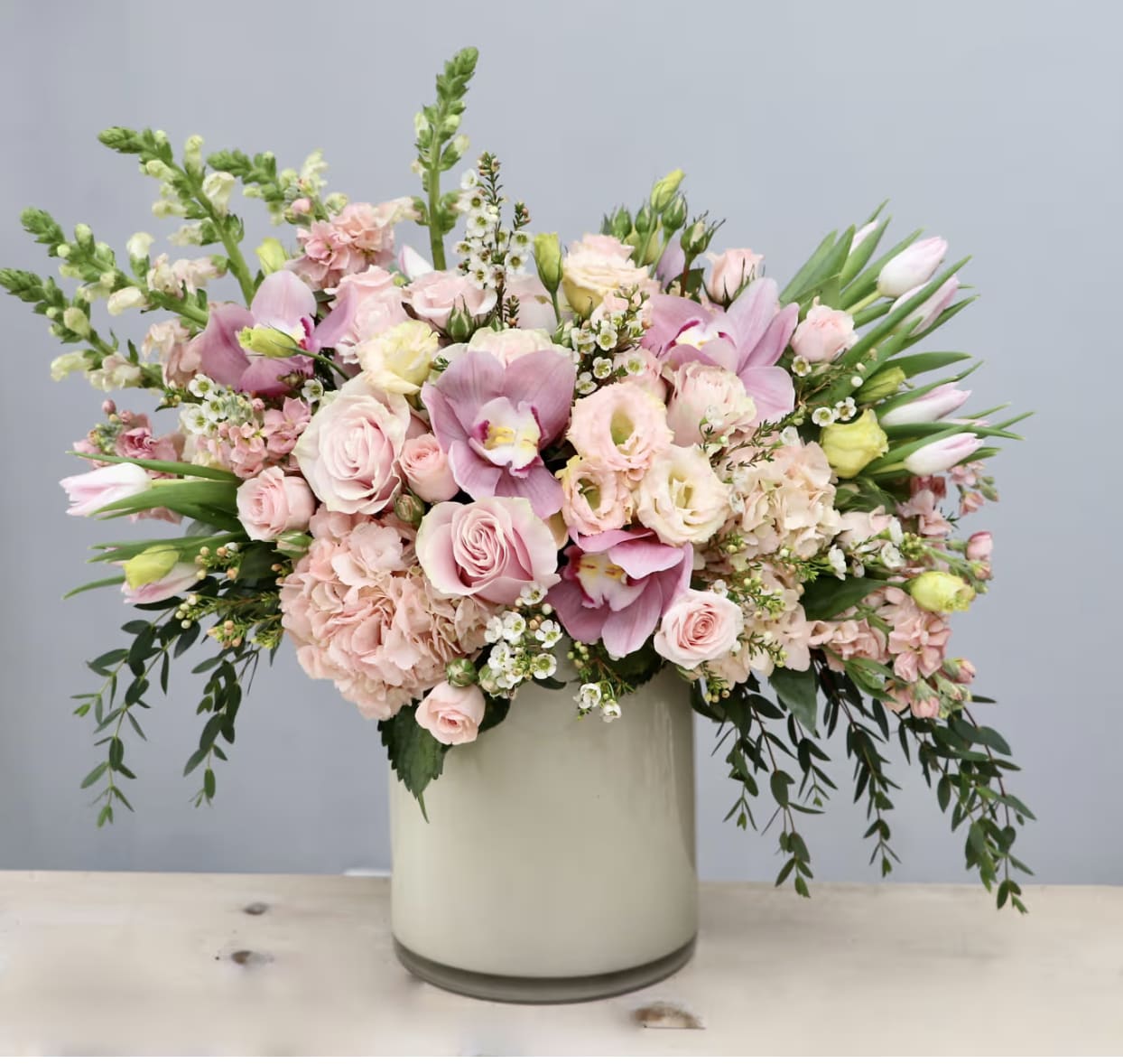 Pink and white floral arrangement in a tall cream vase