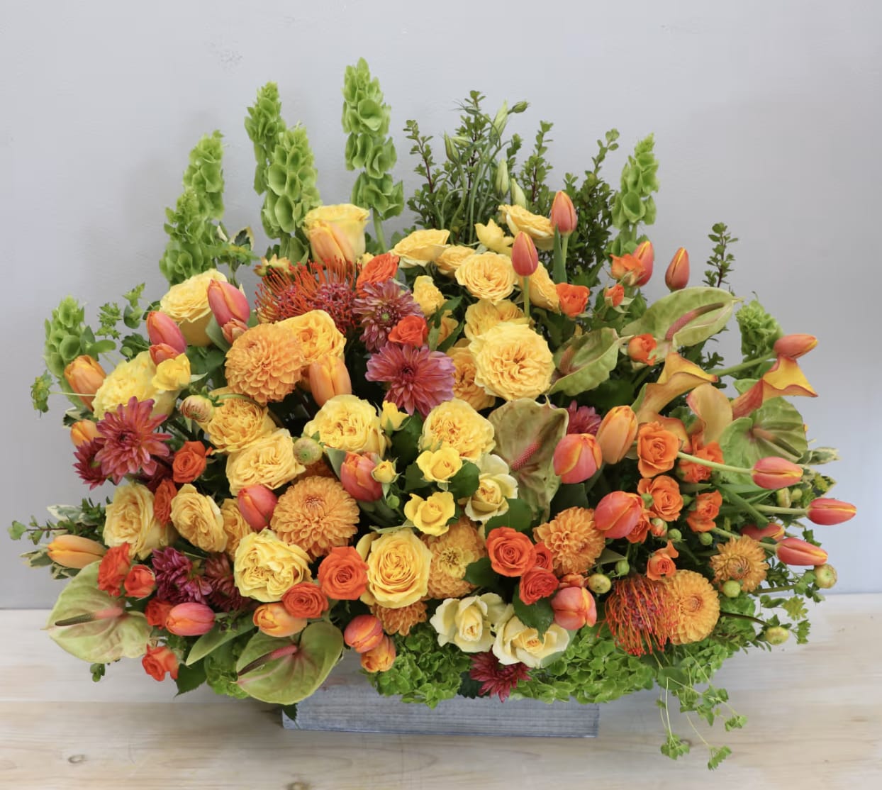 Large orange and yellow floral arrangement in a rectangular container