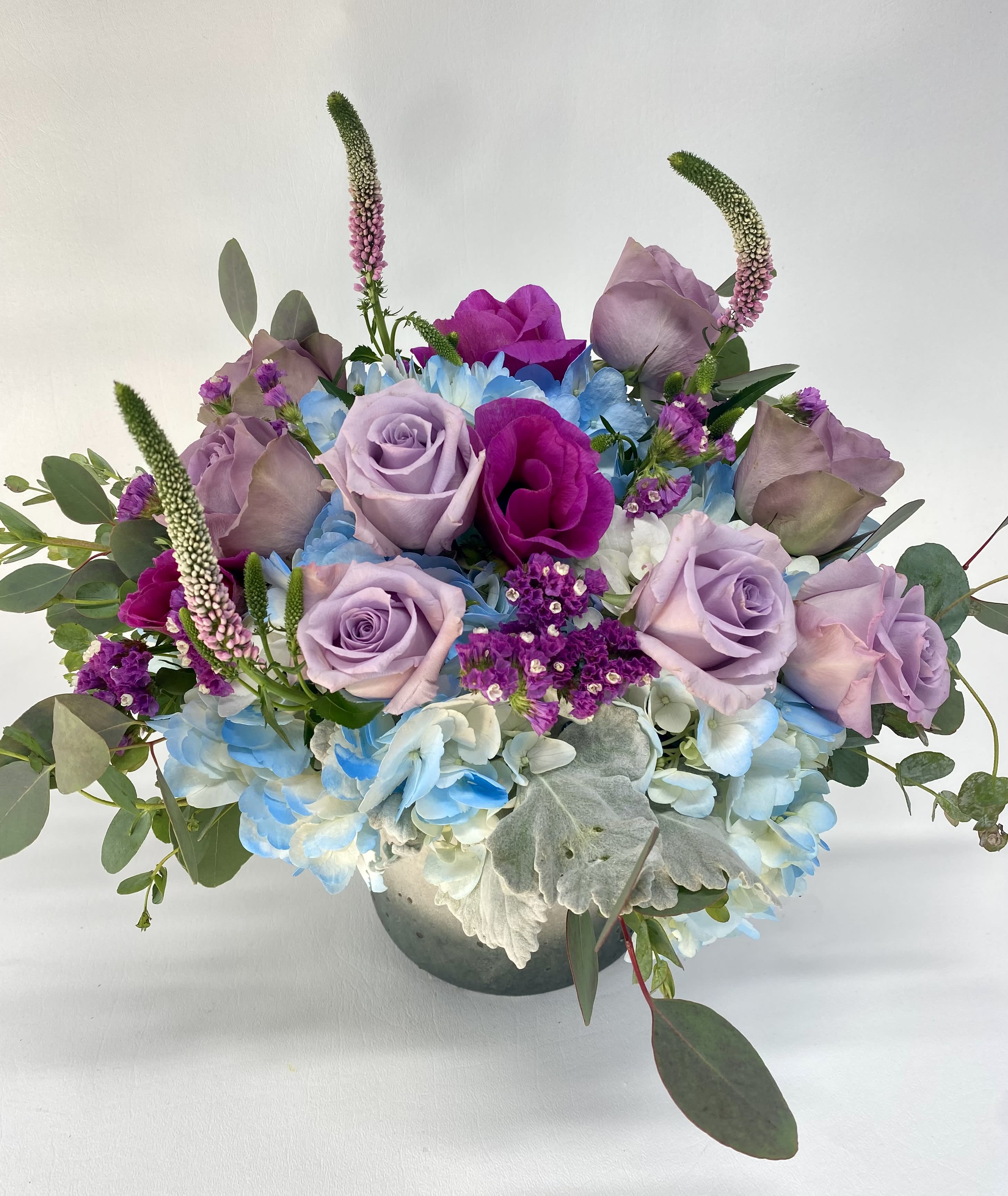 Lavender roses and blue hydrangeas in a low vase arrangement
