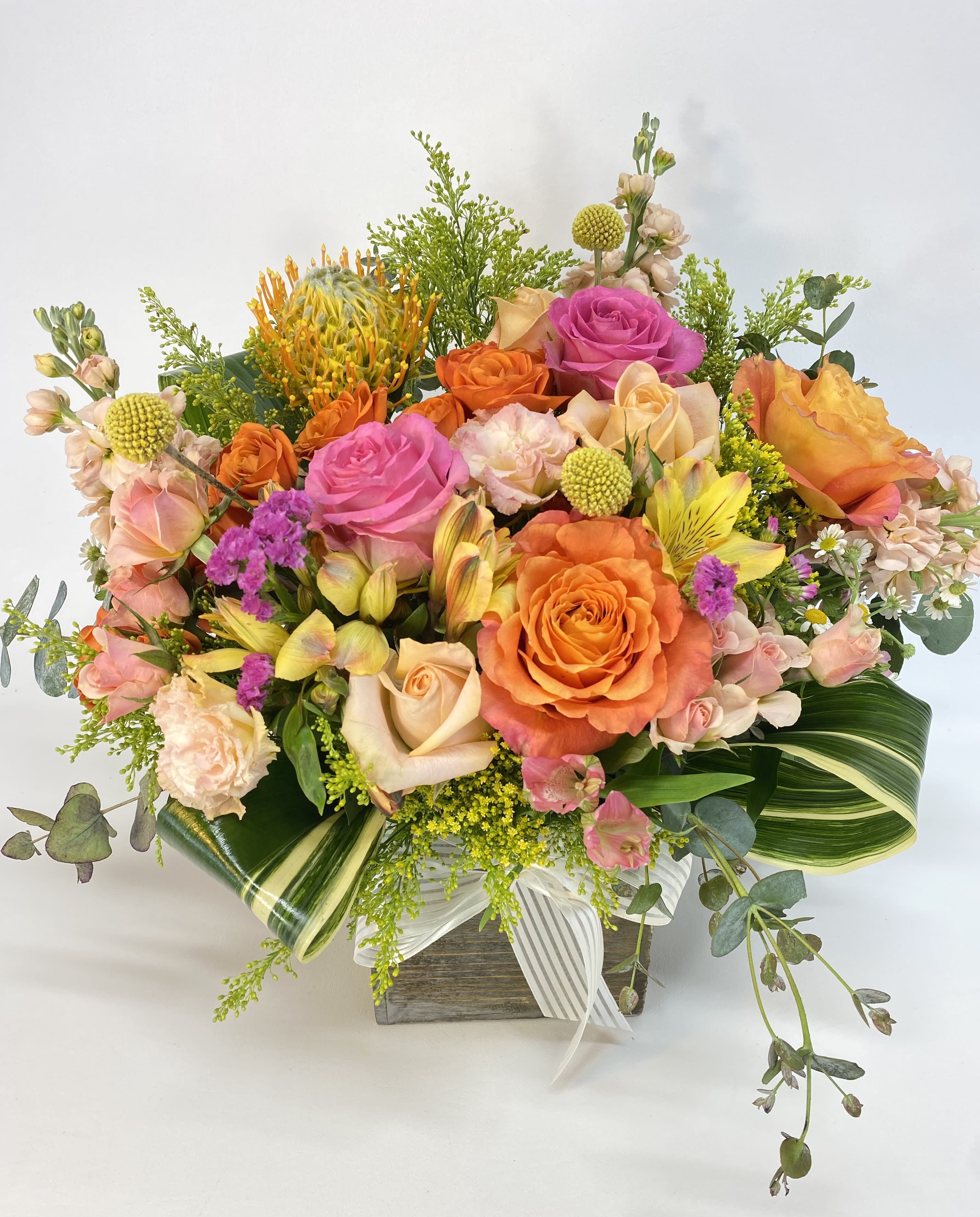 Mixed bouquet of orange and pink roses in a wooden box