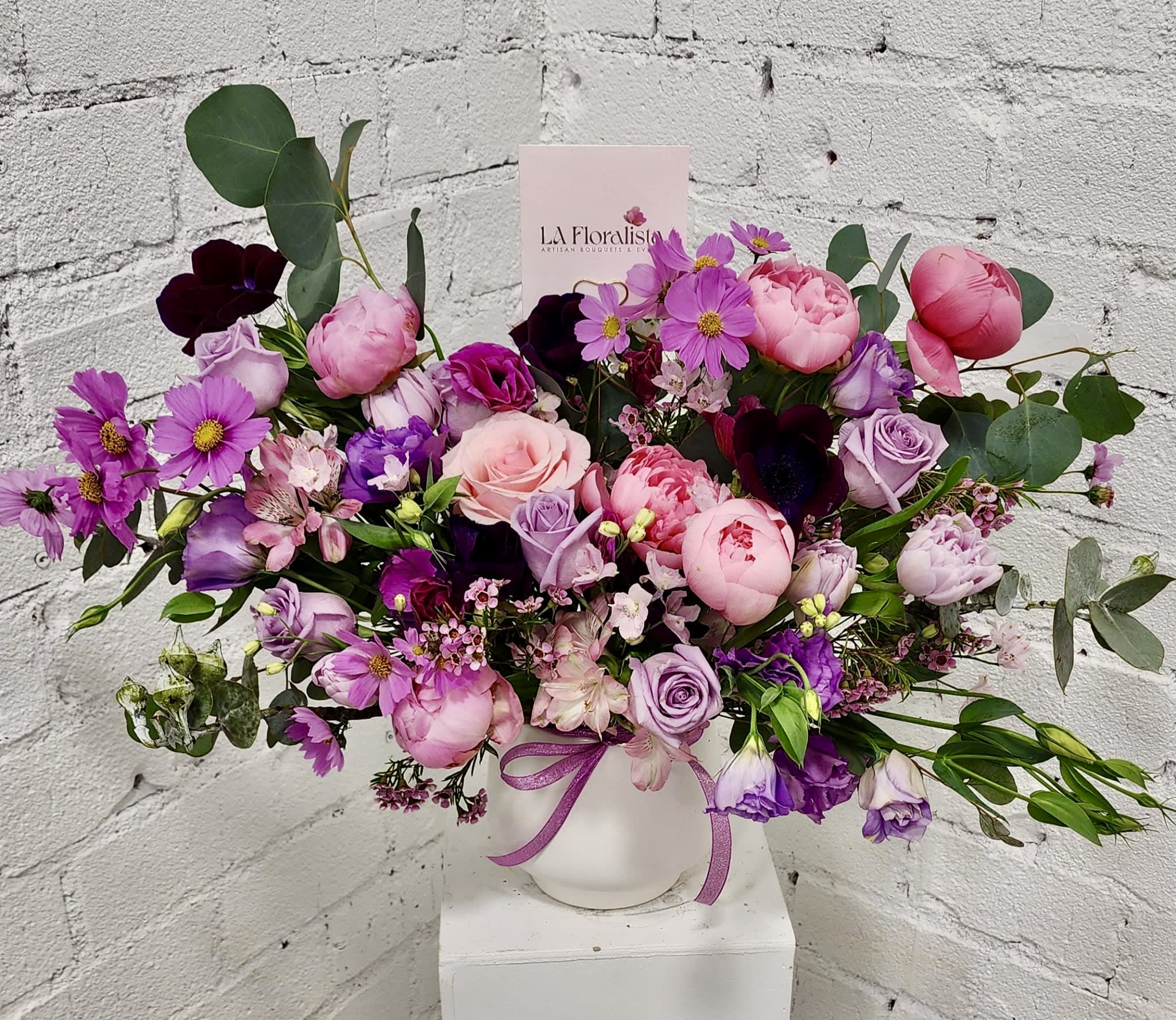 Pink and purple mixed bouquet in a white vase with a ribbon
