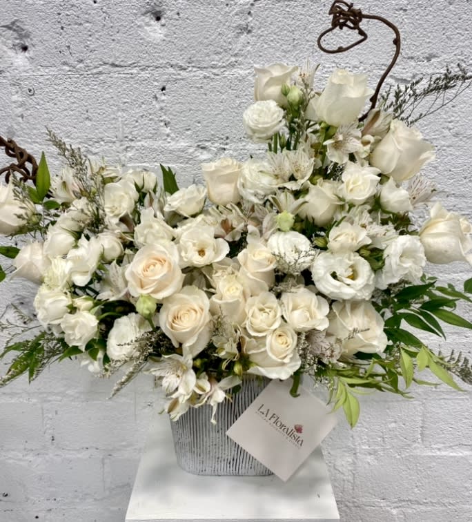 White rose and orchid arrangement in a striped container