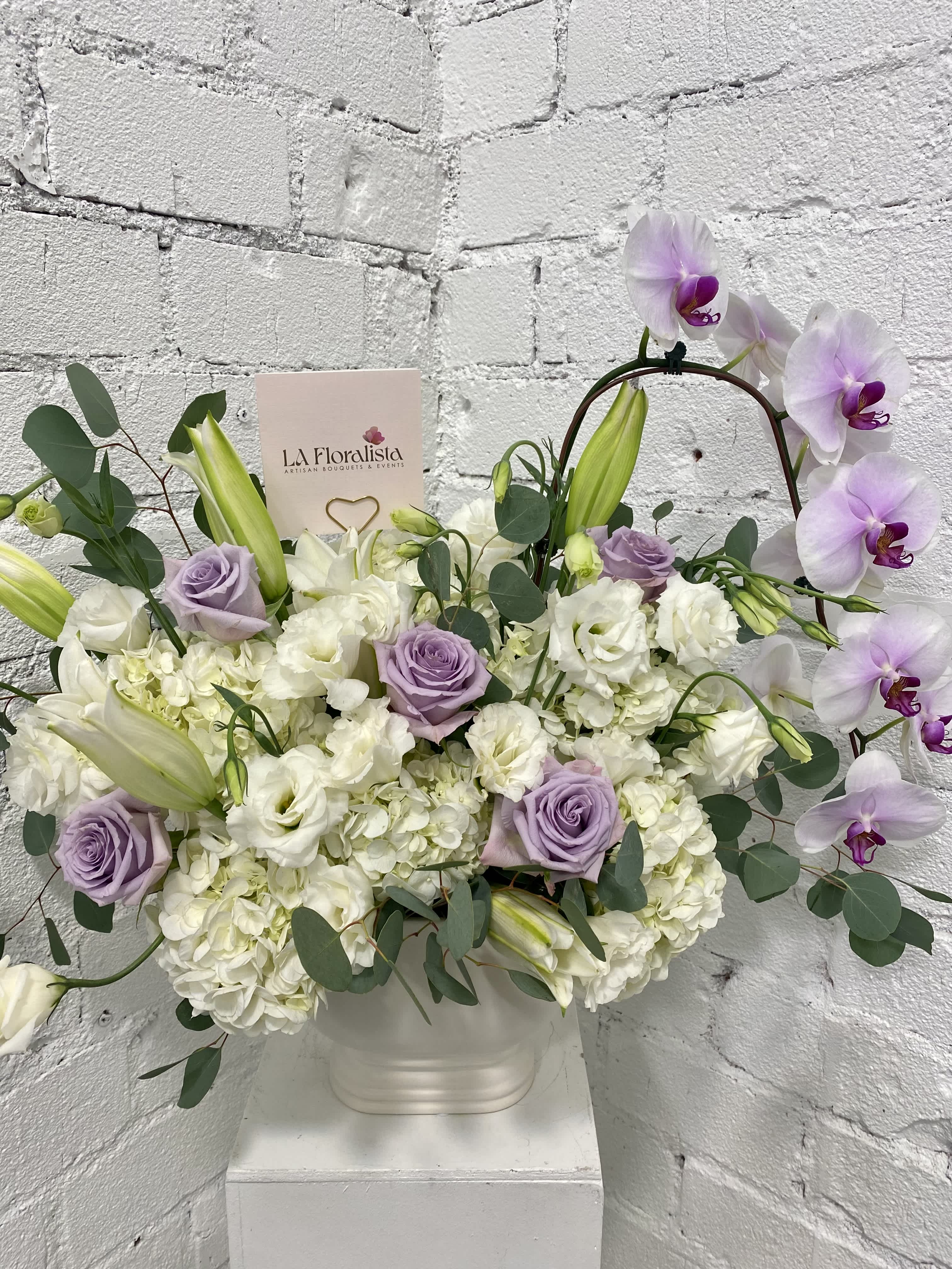 Lavender roses and white orchids in a white vase