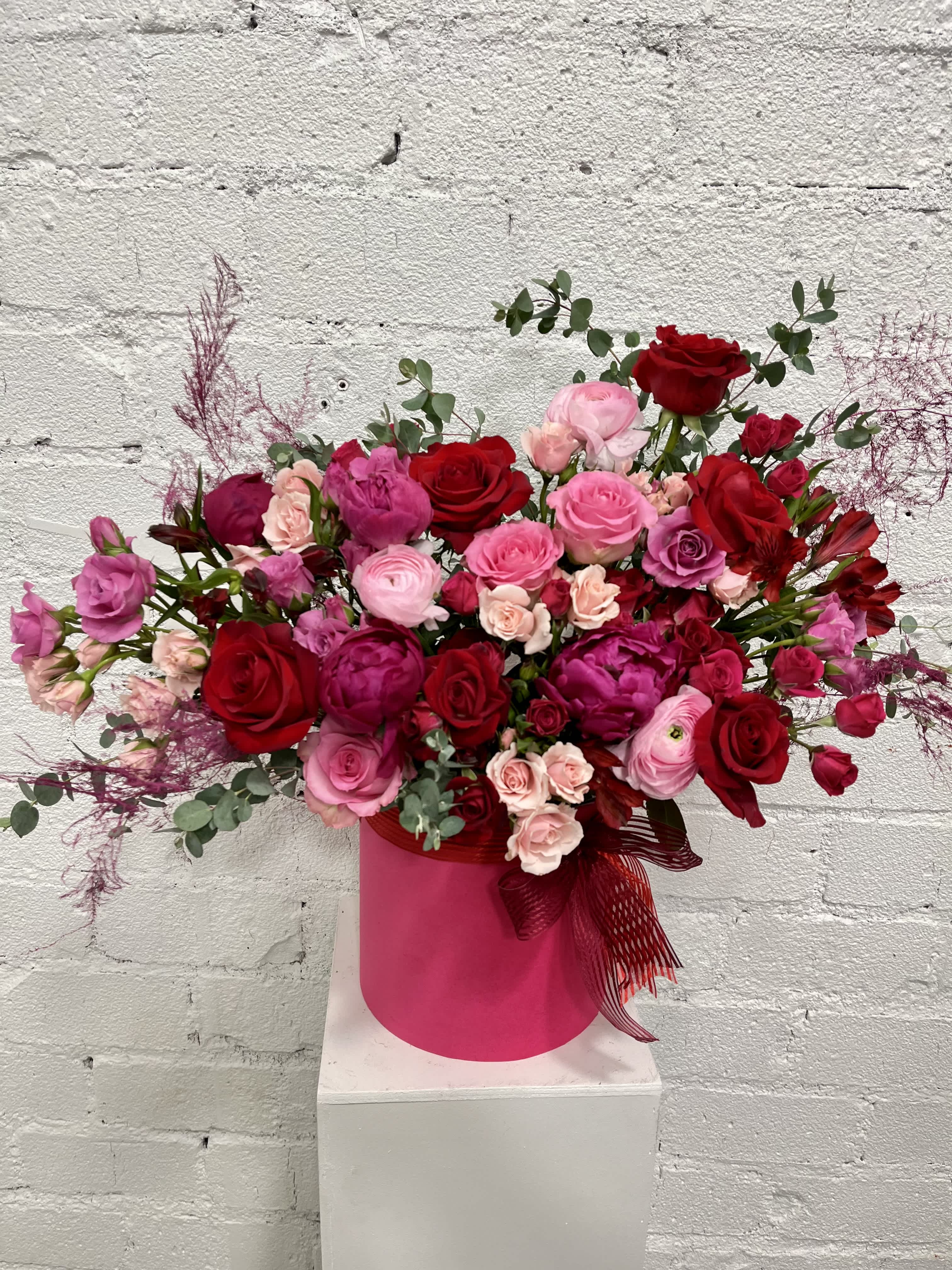 Large bouquet of red and pink roses in a pink hat box