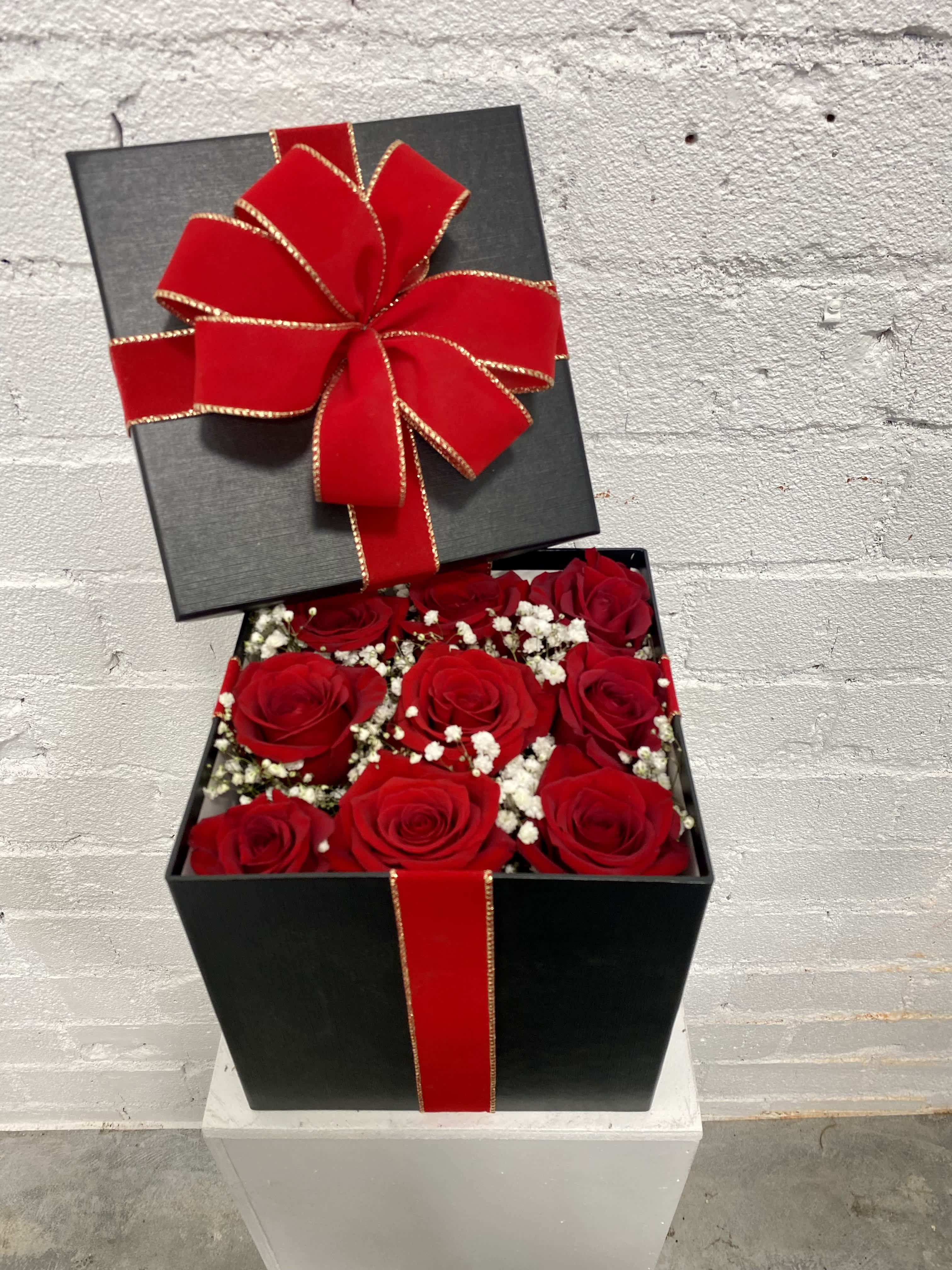 Black gift box with red roses and a large red bow