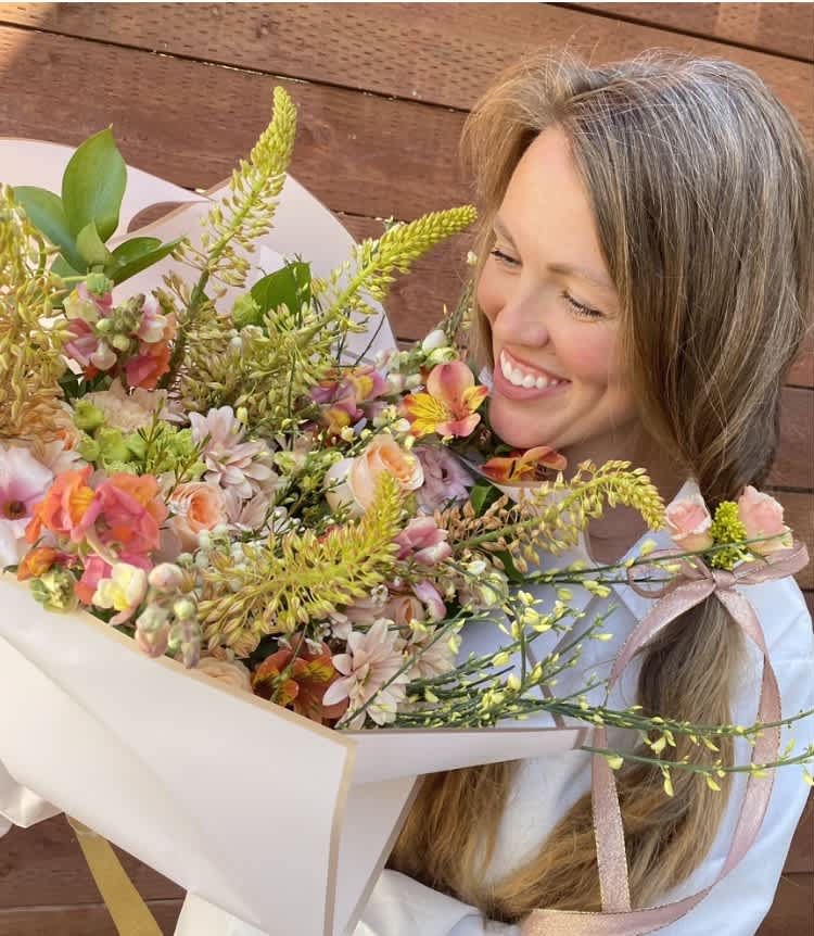 Woman holding a pastel mixed flower bouquet wrapped in white paper