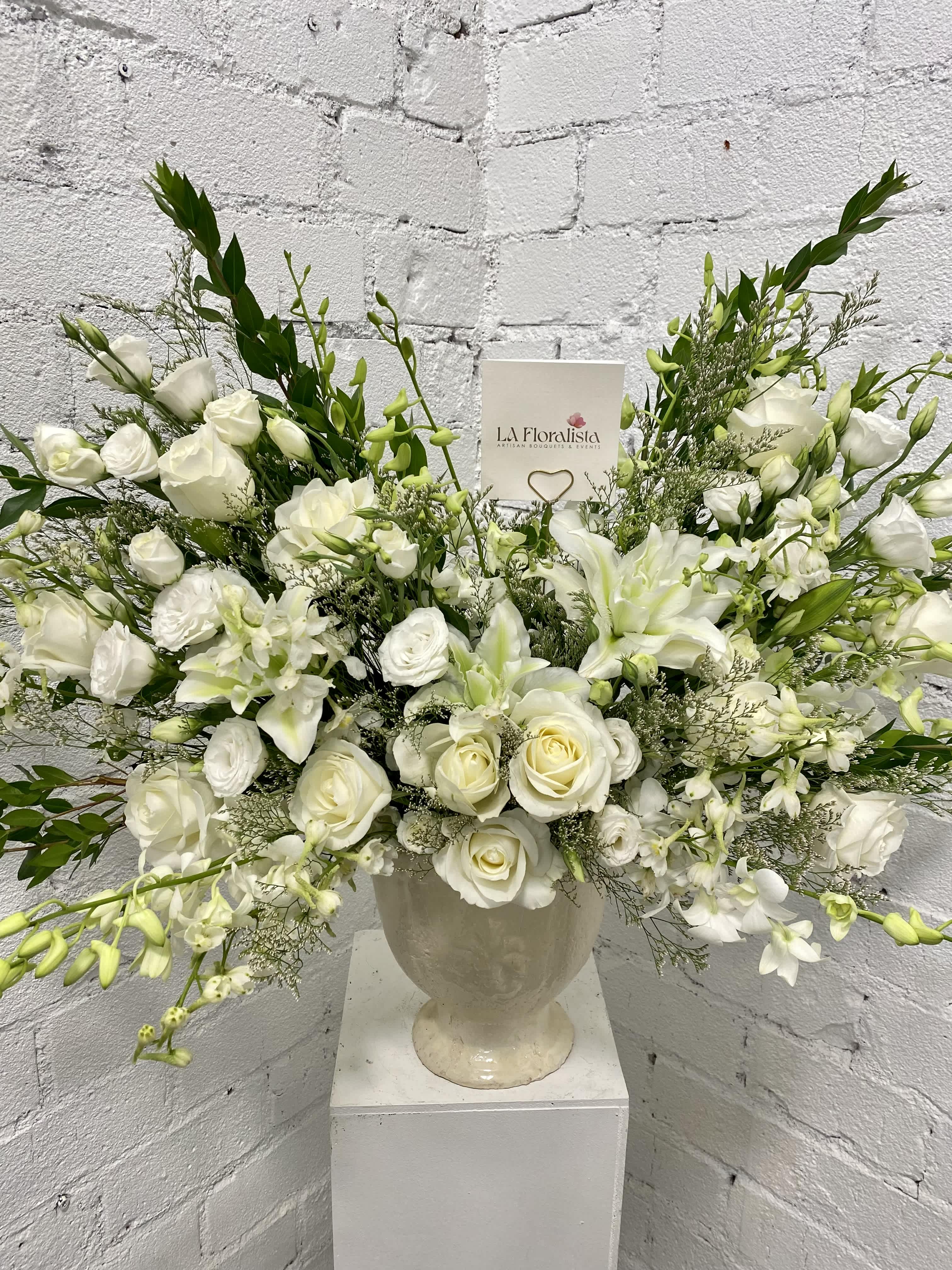 White floral arrangement in a cream urn vase