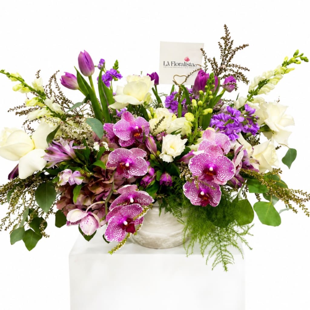 Mixed bouquet with purple orchids, white calla lilies, and tulips in a white vase