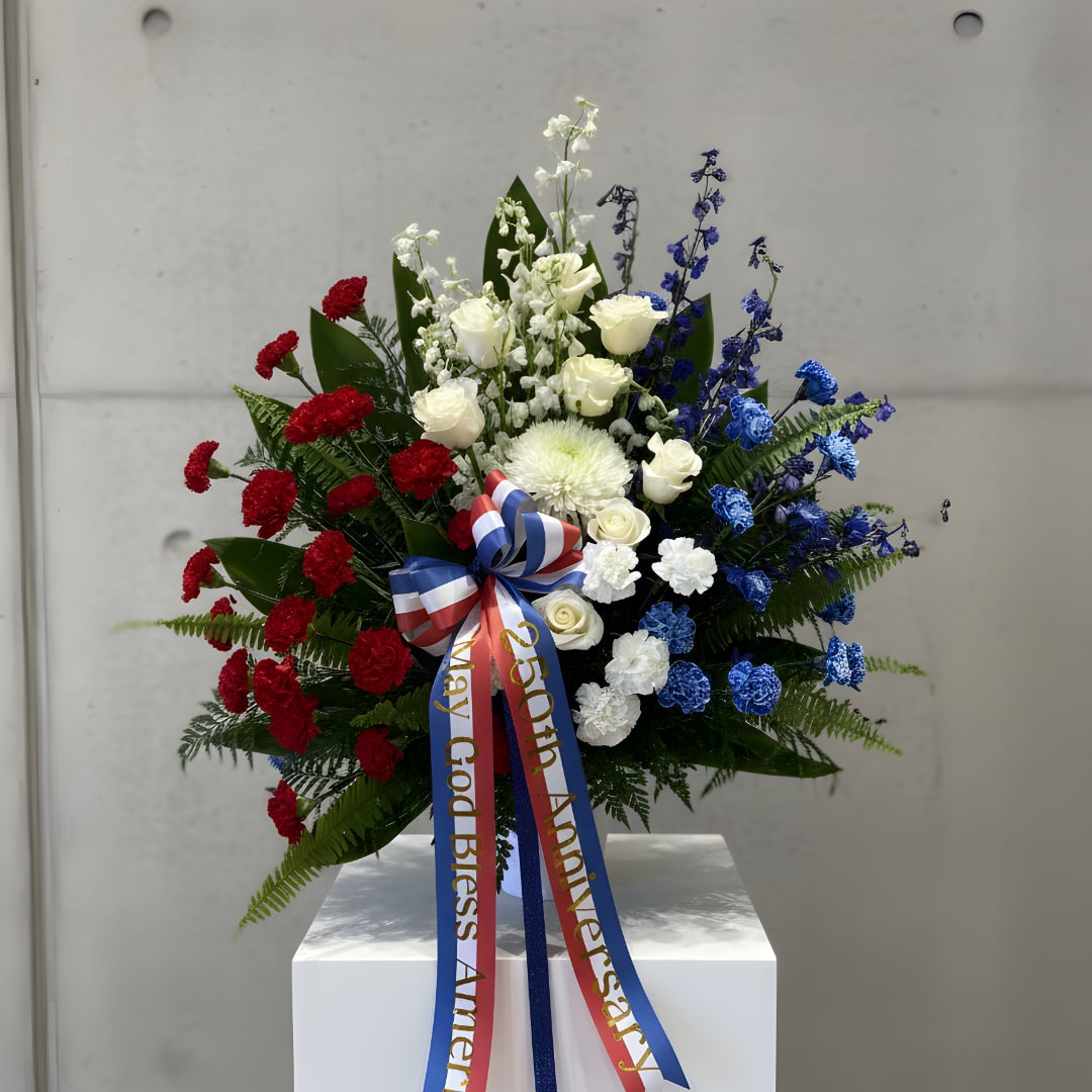 Red, white, and blue floral standing arrangement with a ribbon bow