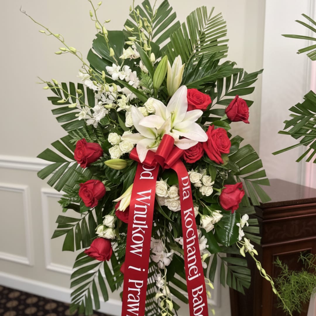Standing floral spray with red and white flowers and a red ribbon