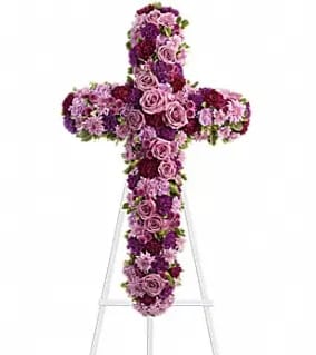 Cross-shaped floral arrangement in pink and purple flowers on an easel