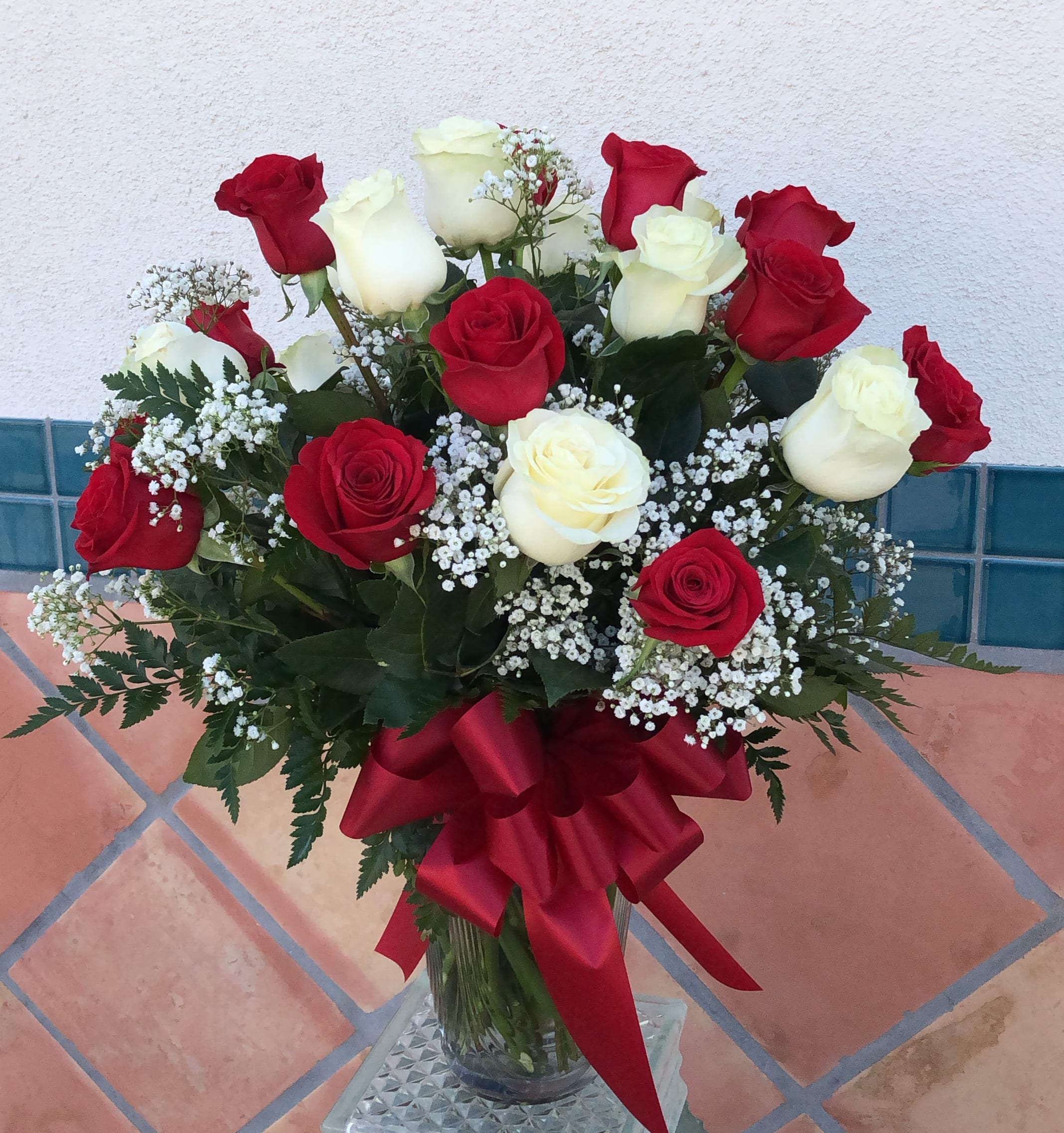 Bouquet of red and white roses in a glass vase with a red ribbon
