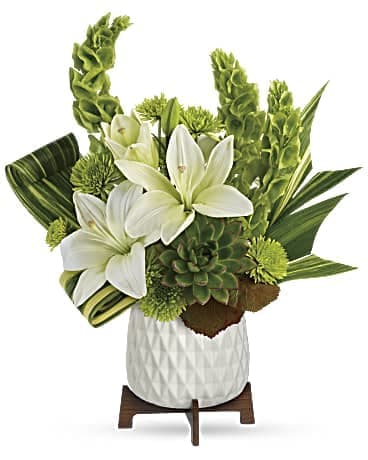 White lilies and green tropical flowers in a white vase