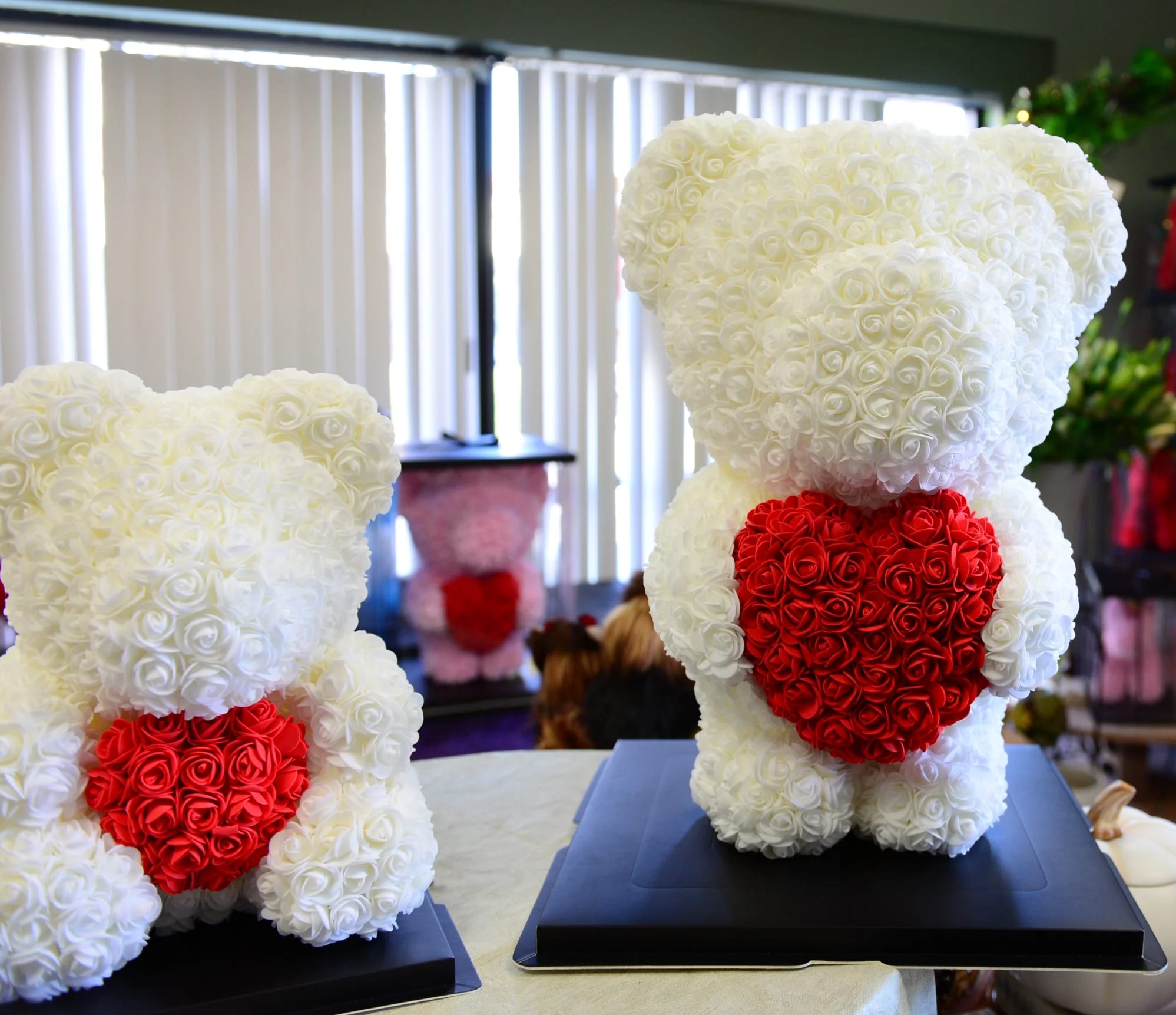 Two teddy bears made of white and red roses on black bases