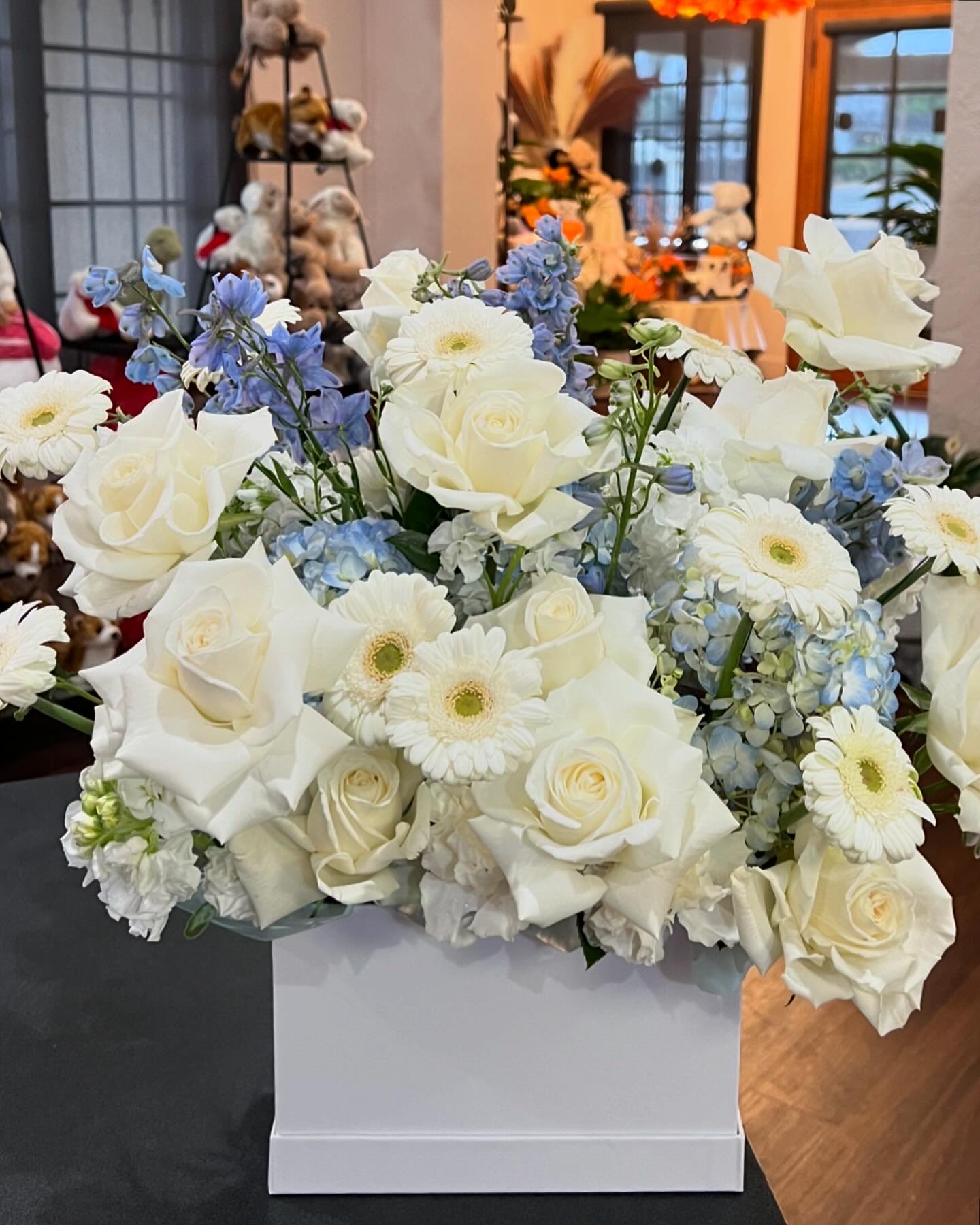 Elegance in white and blue flower box - A mixed of Hydrangea, gerbera, roses, carnation, stock, and delphinium in blue and white are artistically arranged inside a white flower box. 