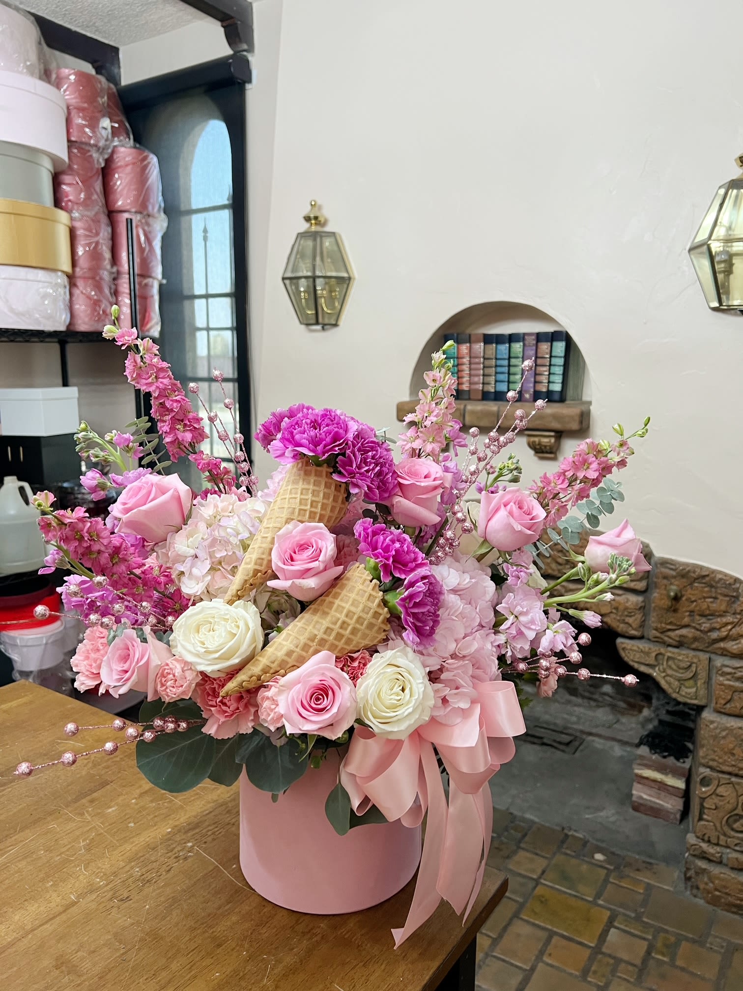 Pink and white rose arrangement in a pink hatbox with waffle cones