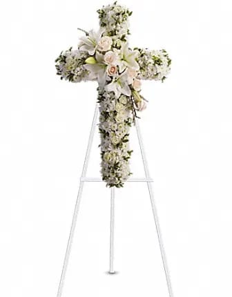 White floral cross on a stand with lilies and roses