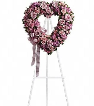 Heart-shaped pink rose wreath on a white easel with ribbon