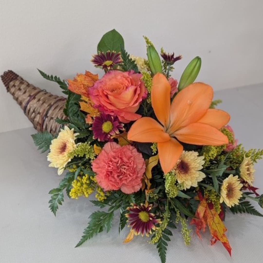 Orange and pink mixed bouquet with lilies, roses, and carnations in a woven cone wrap