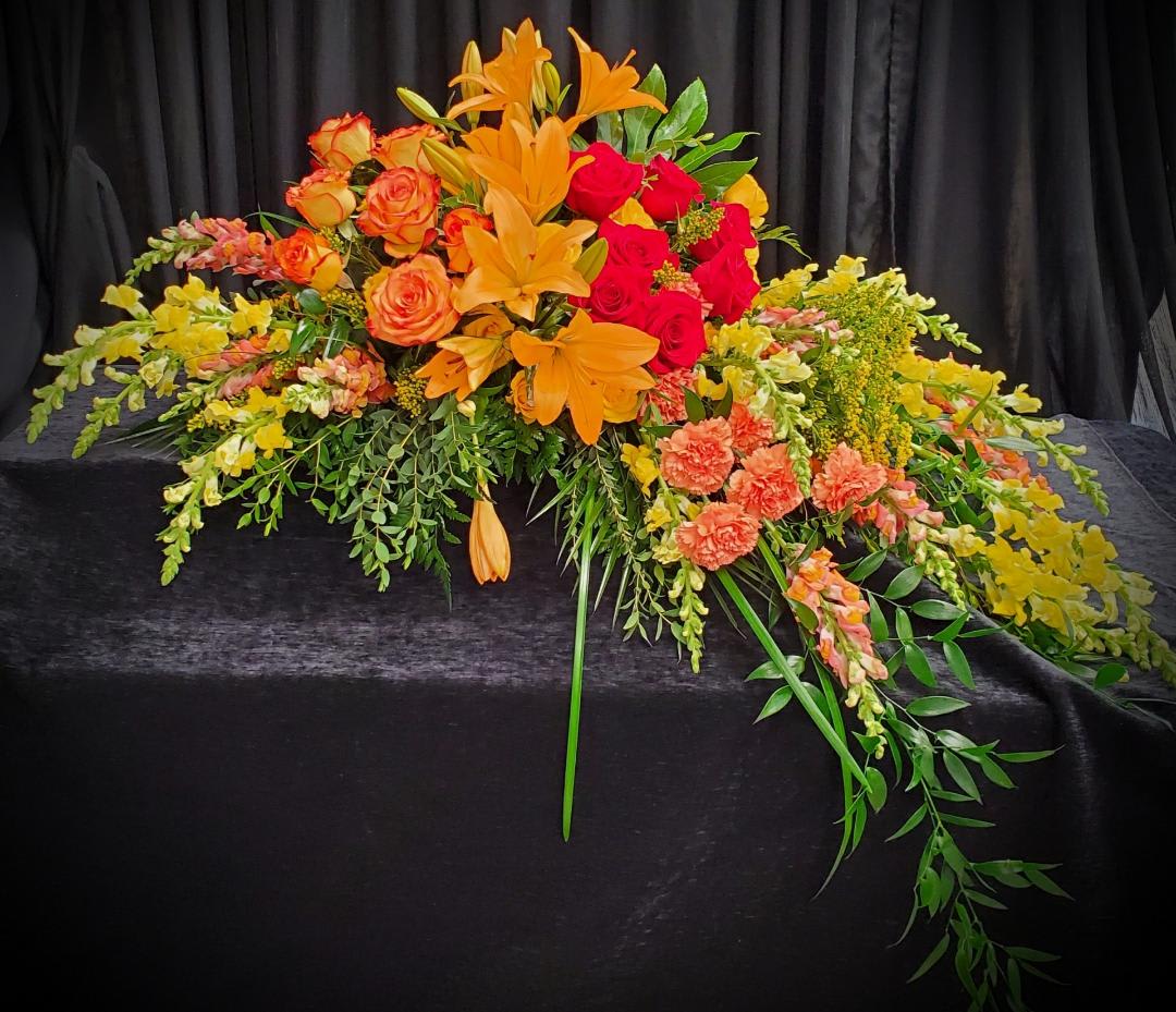 Large floral arrangement with orange lilies and red and orange roses