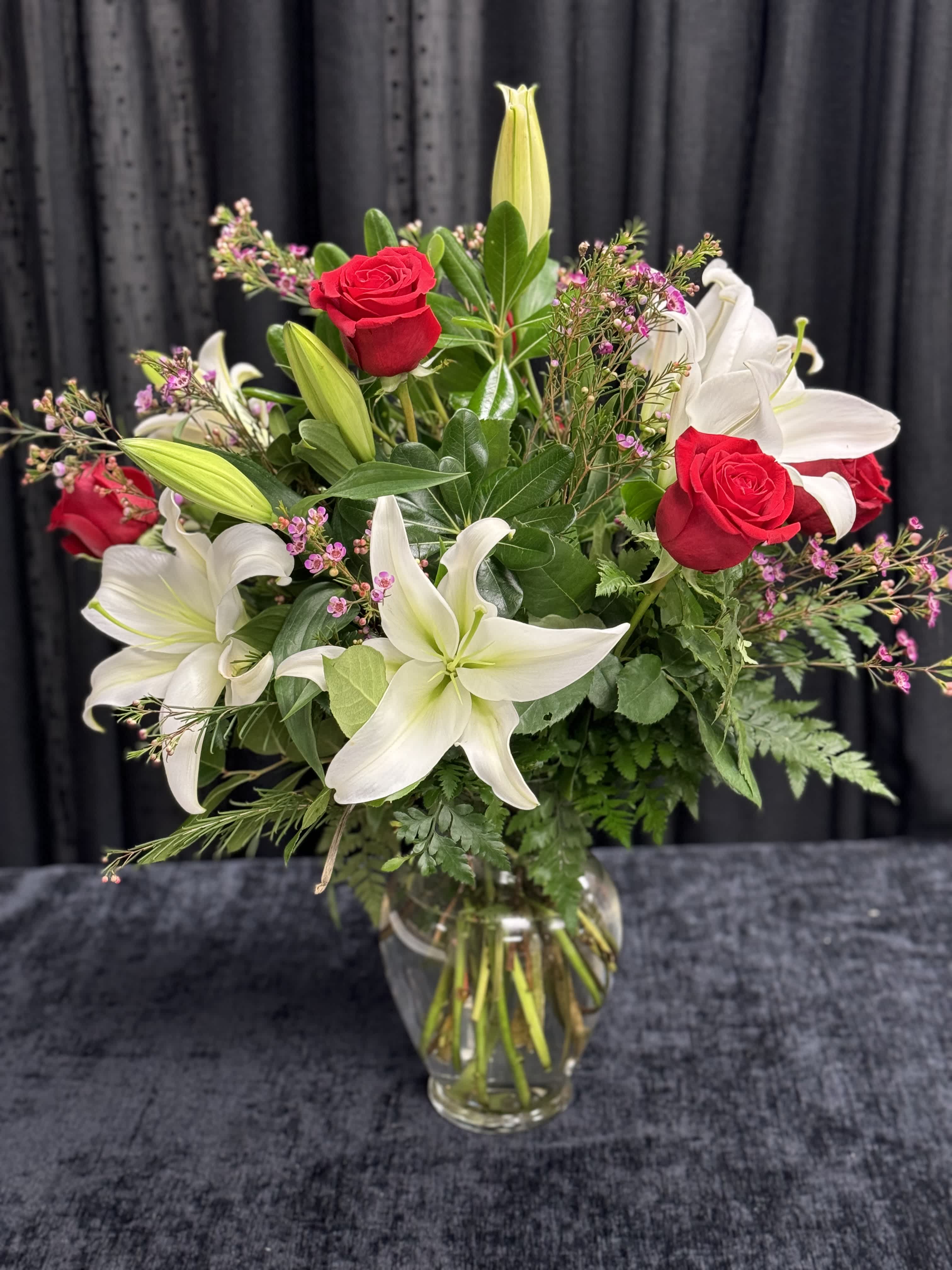 Bouquet of red roses and white lilies in a clear glass vase