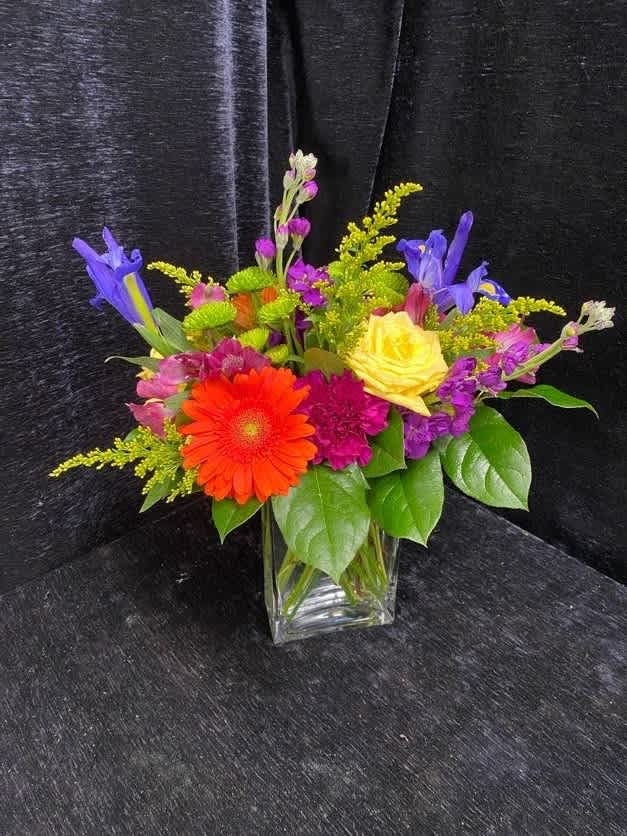 Colorful mixed bouquet in a clear glass vase with gerbera daisies and roses