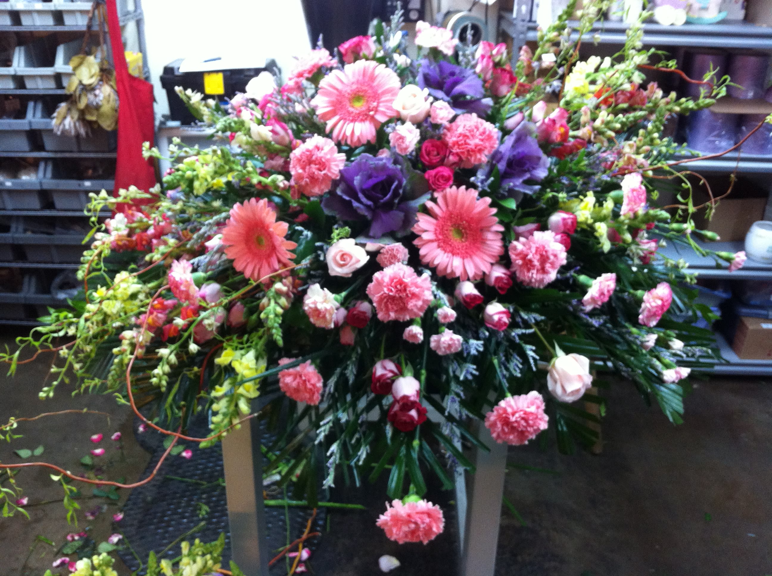 Large mixed floral spray with pink and purple blooms on a stand