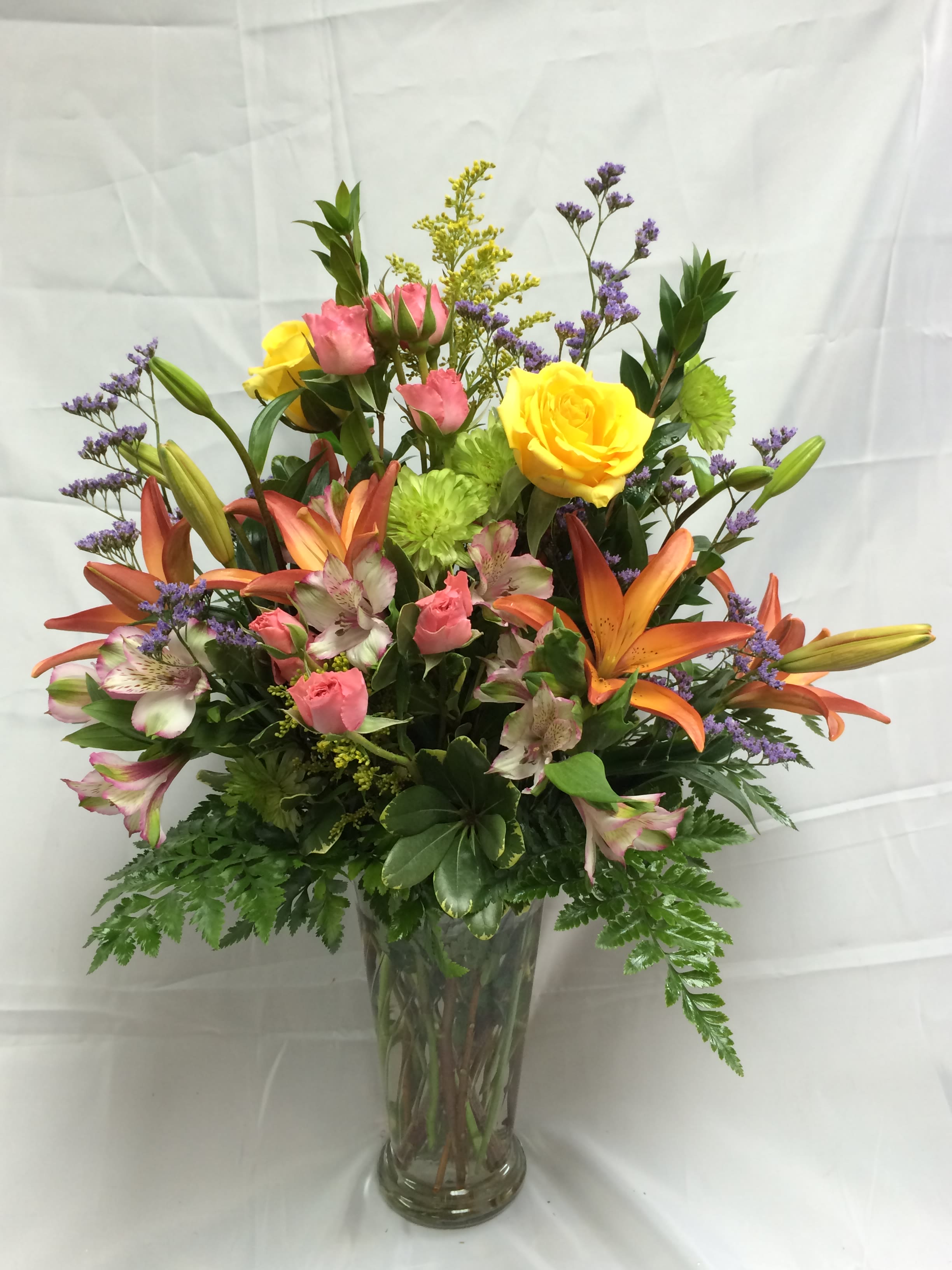 Mixed bouquet of roses, lilies, and alstroemeria in a glass vase