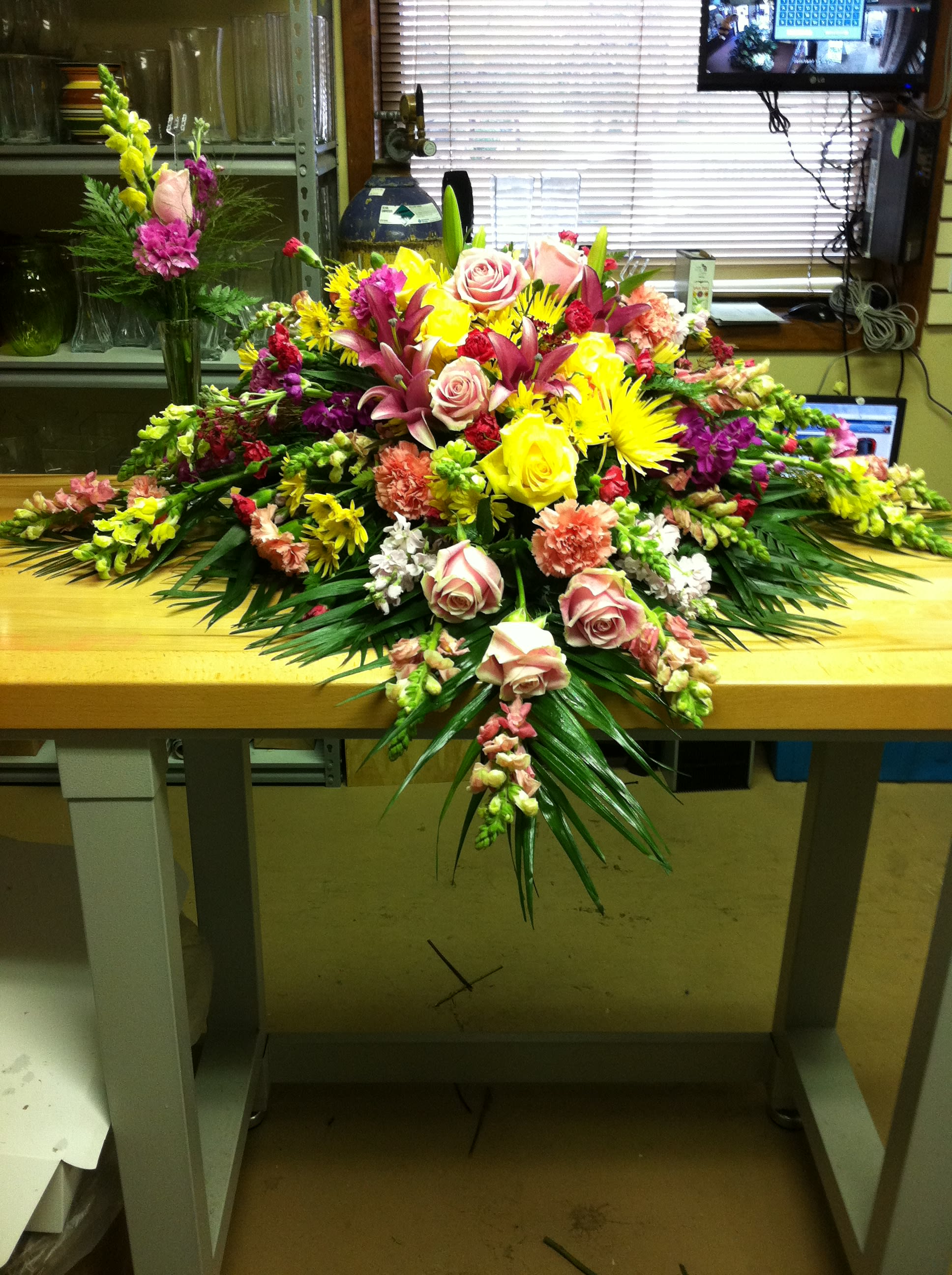 Large mixed floral arrangement with roses, lilies, and bright yellow blooms
