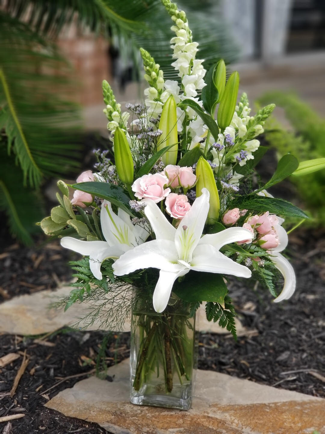 White lilies and pink roses arranged in a glass vase