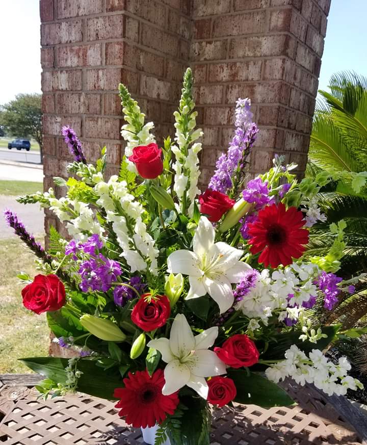 Mixed bouquet with red roses, white lilies, and purple flowers in a vase