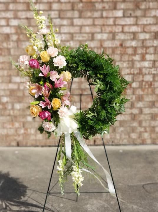 Floral wreath on a stand with pink, yellow, and white blooms