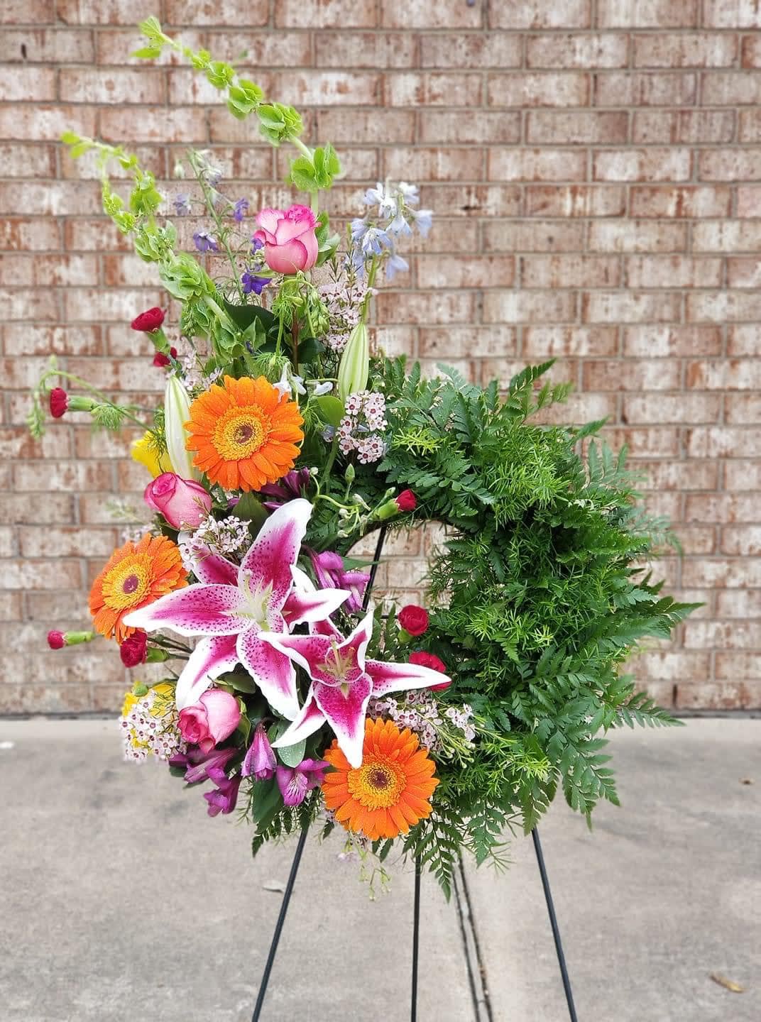 Colorful floral wreath with lilies, gerberas, and roses on a stand