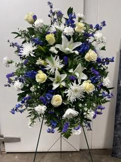 Standing floral spray with white and blue flowers on a metal easel