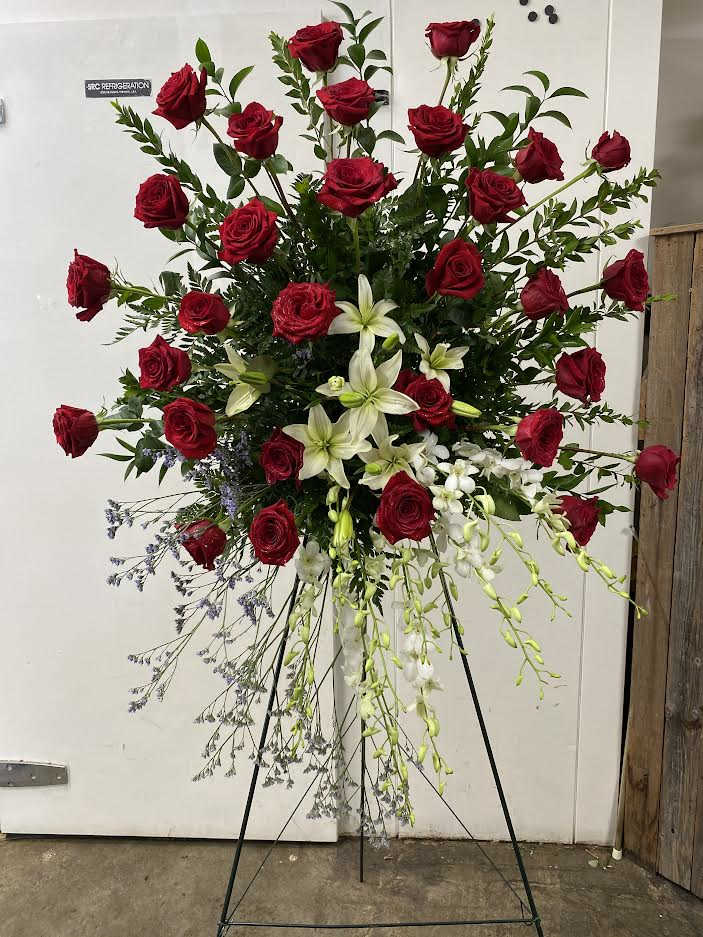 Tall standing spray of red roses and white lilies on a metal easel