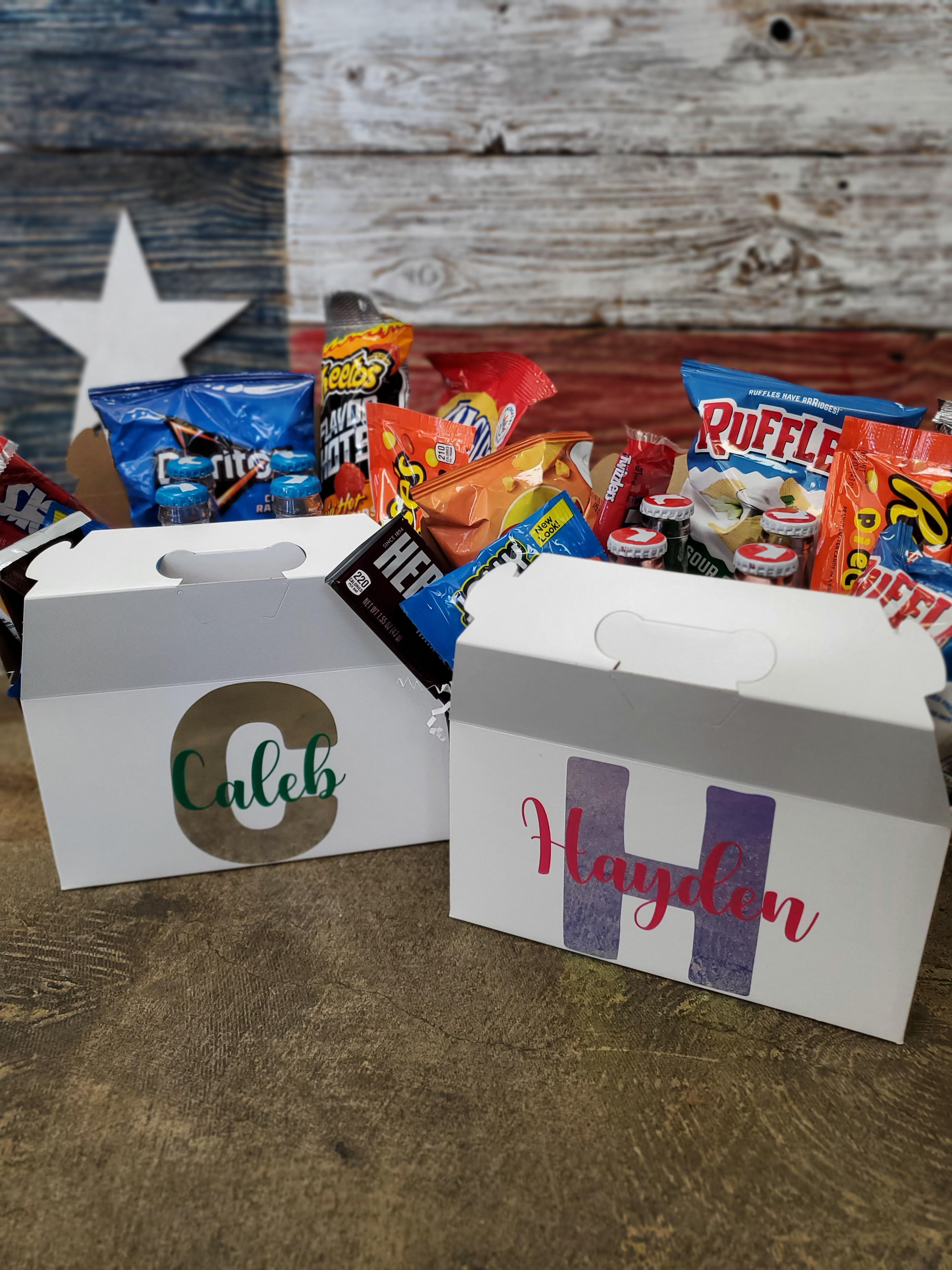 Two personalized snack boxes filled with assorted chips and candy