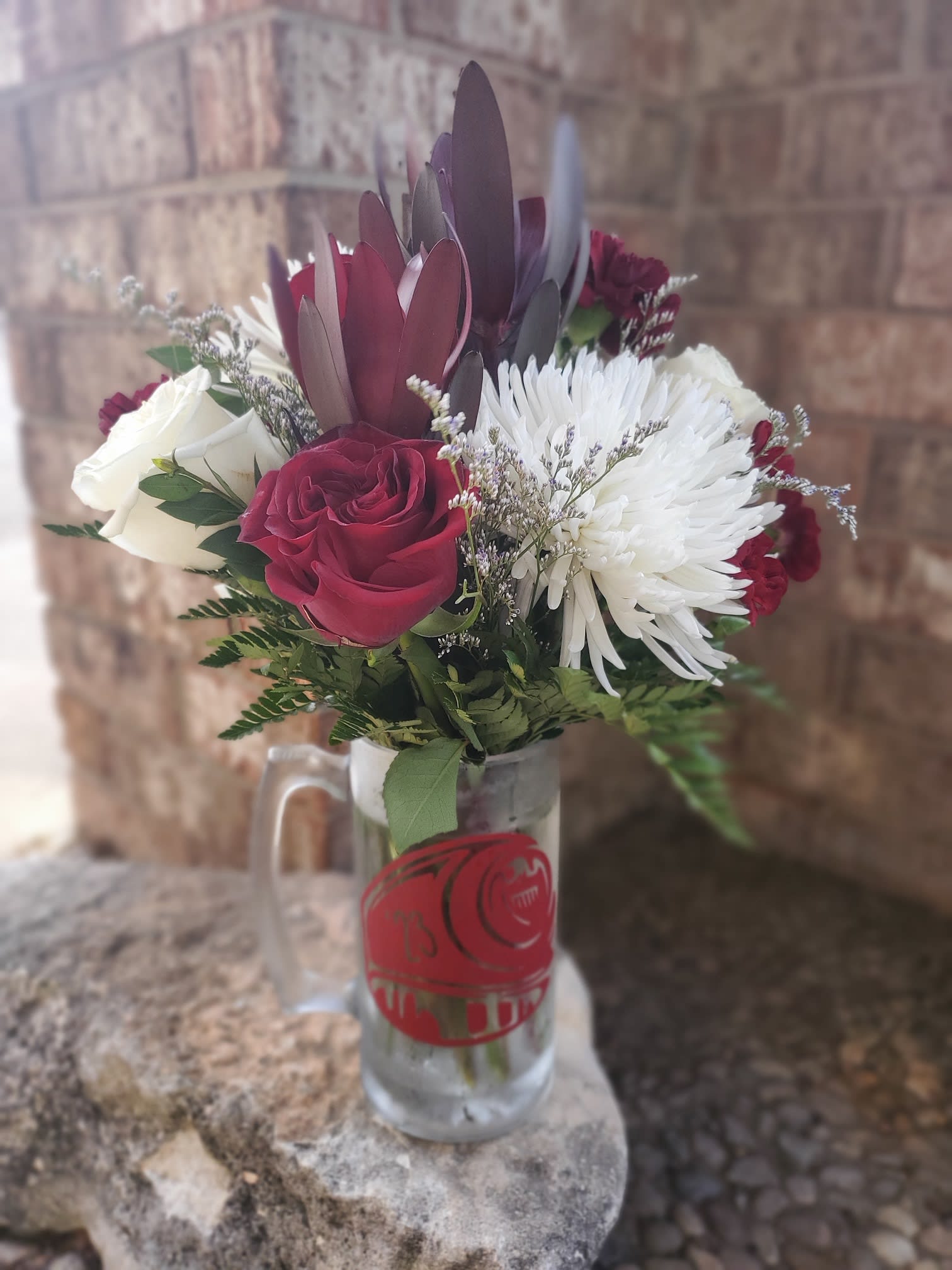 Bouquet of red and white roses with white chrysanthemum in a glass mug