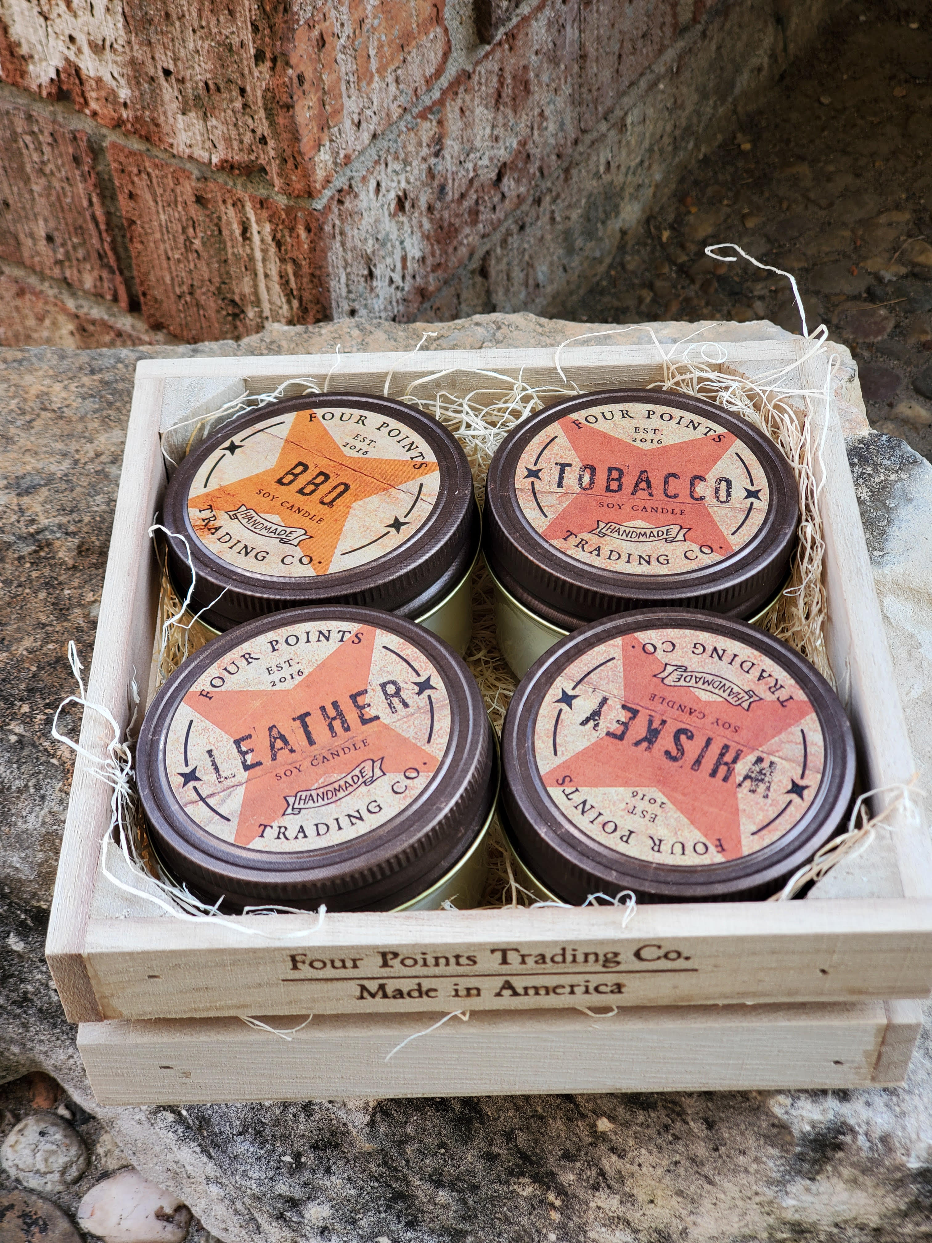 Four scented candles in a wooden crate with shredded filler