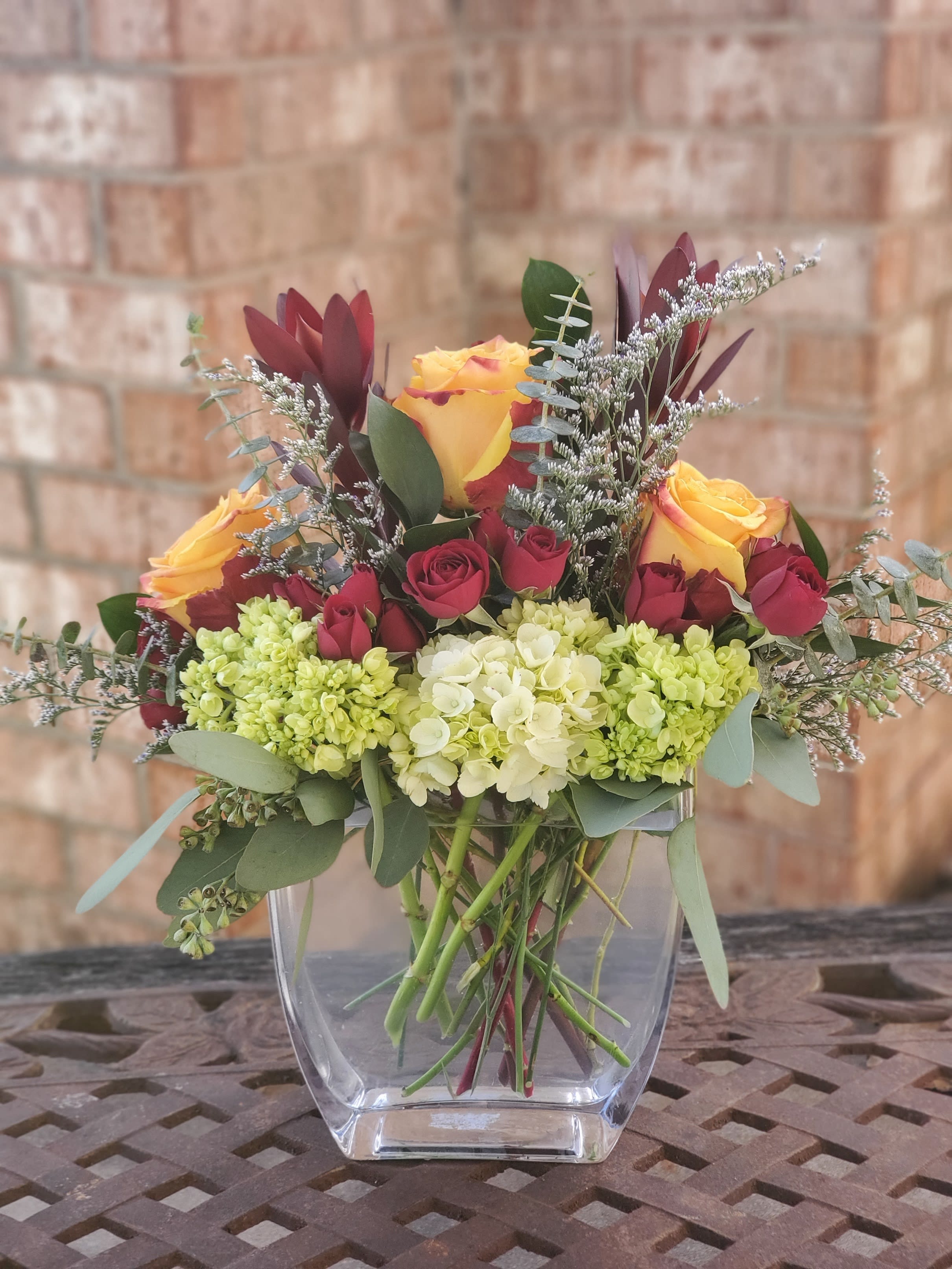 Bouquet of yellow and red roses in a clear glass vase