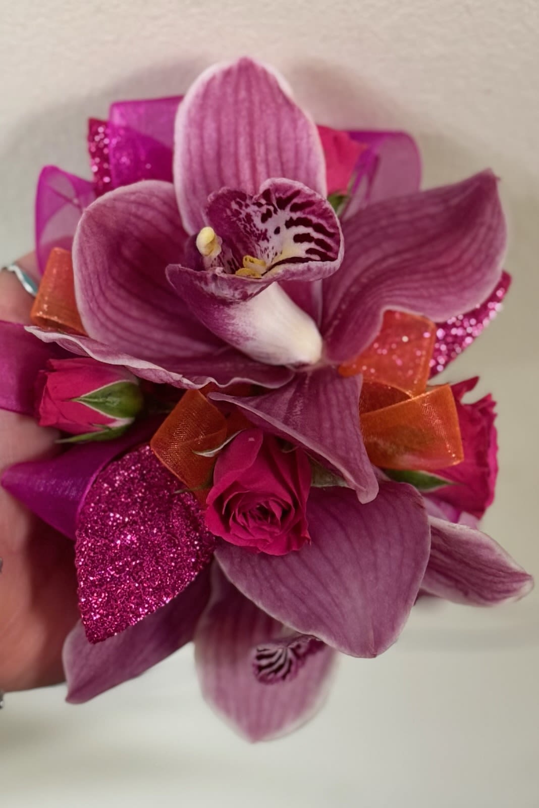 Pink orchid and rose corsage with orange ribbon accents