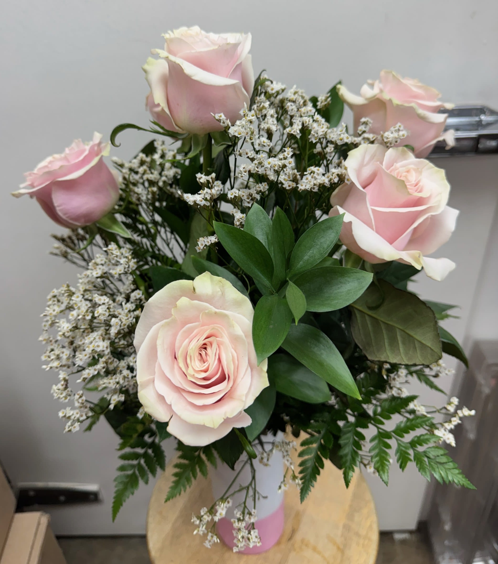 Bouquet of pale pink roses with white filler flowers in a pink vase