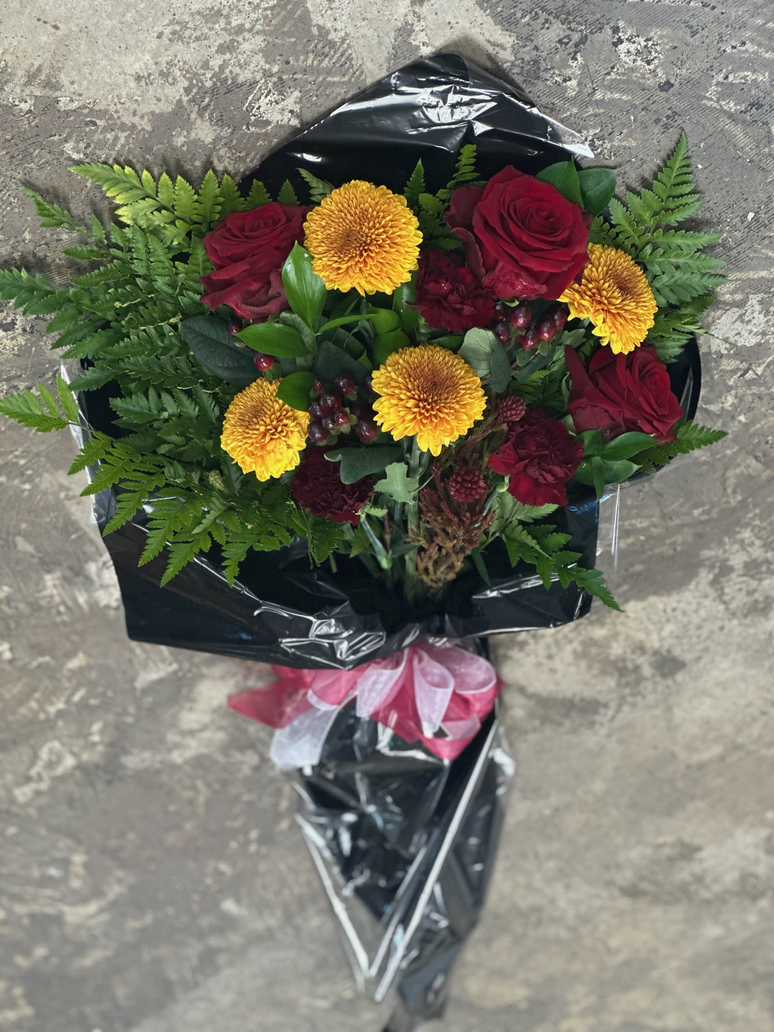 Bouquet of red roses and yellow chrysanthemums wrapped in black paper
