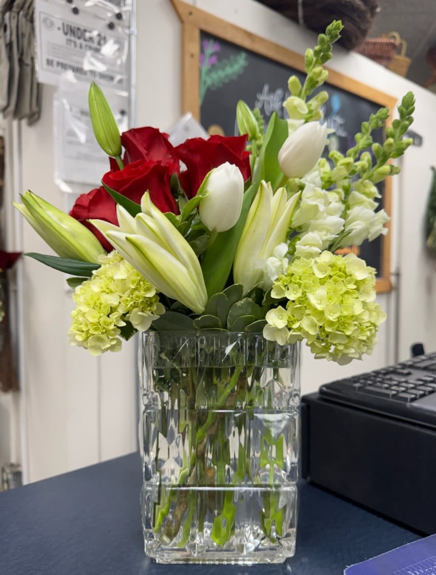 Red roses and white tulips in a clear glass vase