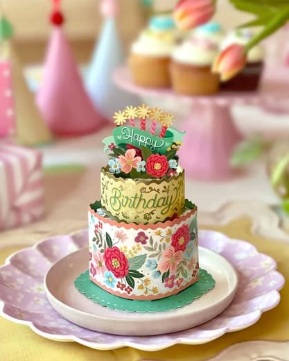 Tiered birthday cake with floral decorations and pastel party accents