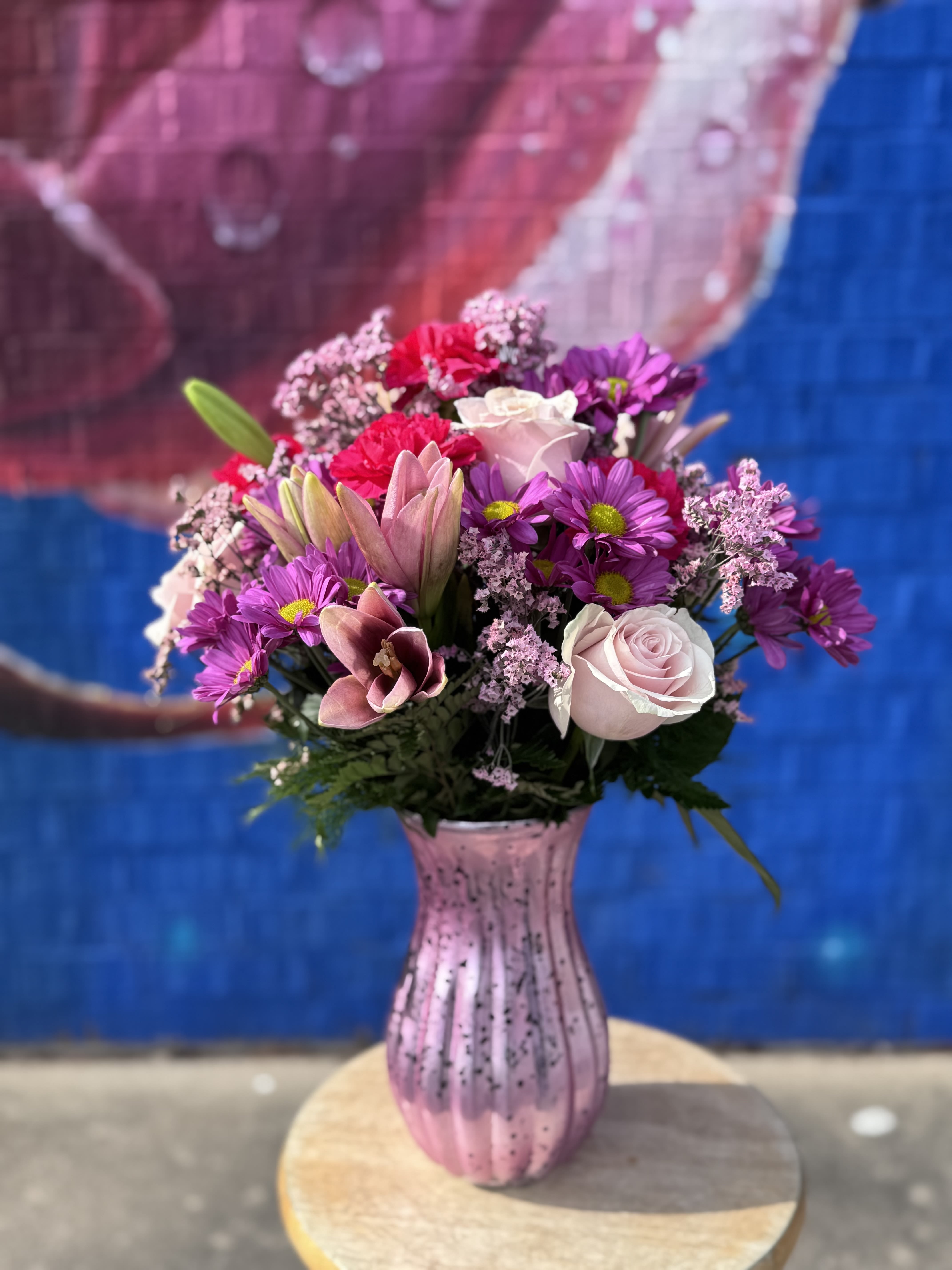 Pink and purple mixed bouquet in a pink glass vase