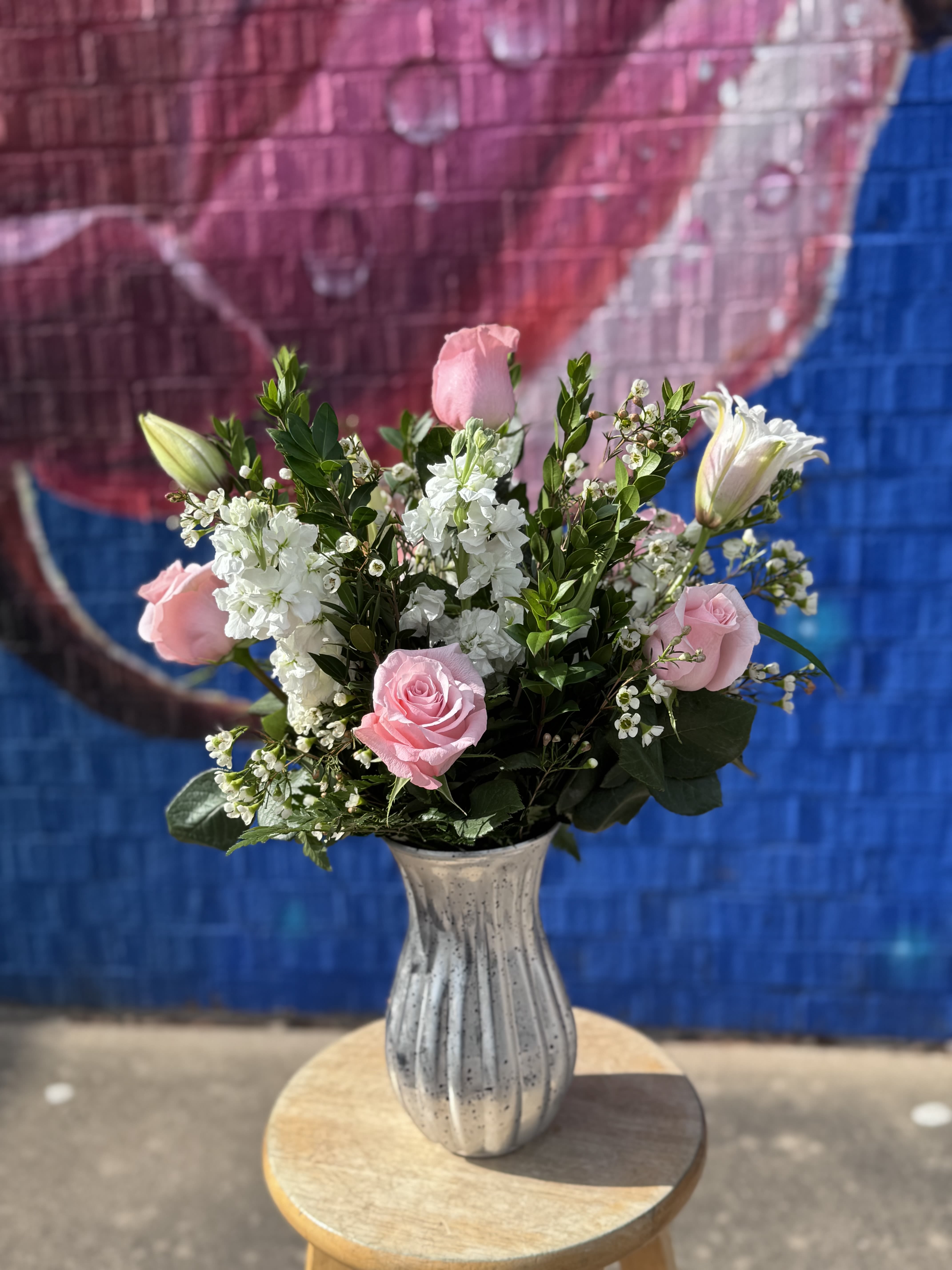 Pink roses and white flowers arranged in a silver vase