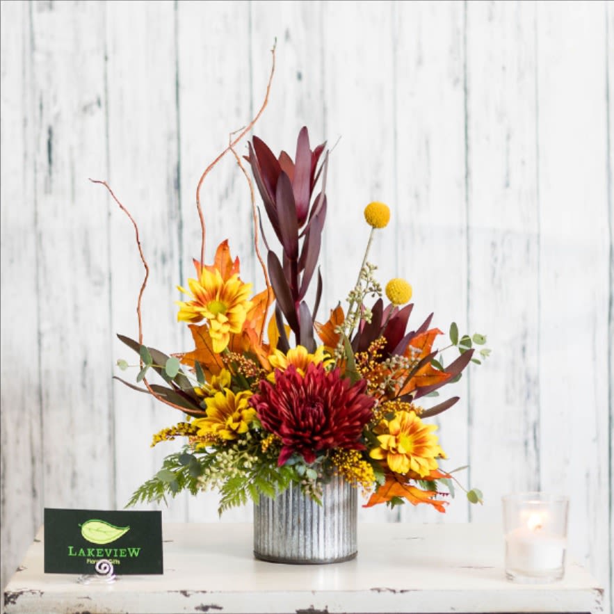 Autumn floral arrangement with red and yellow blooms in a ribbed metal vase