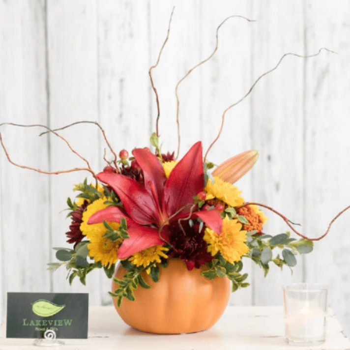 Pumpkin-shaped vase with red lilies and yellow mums