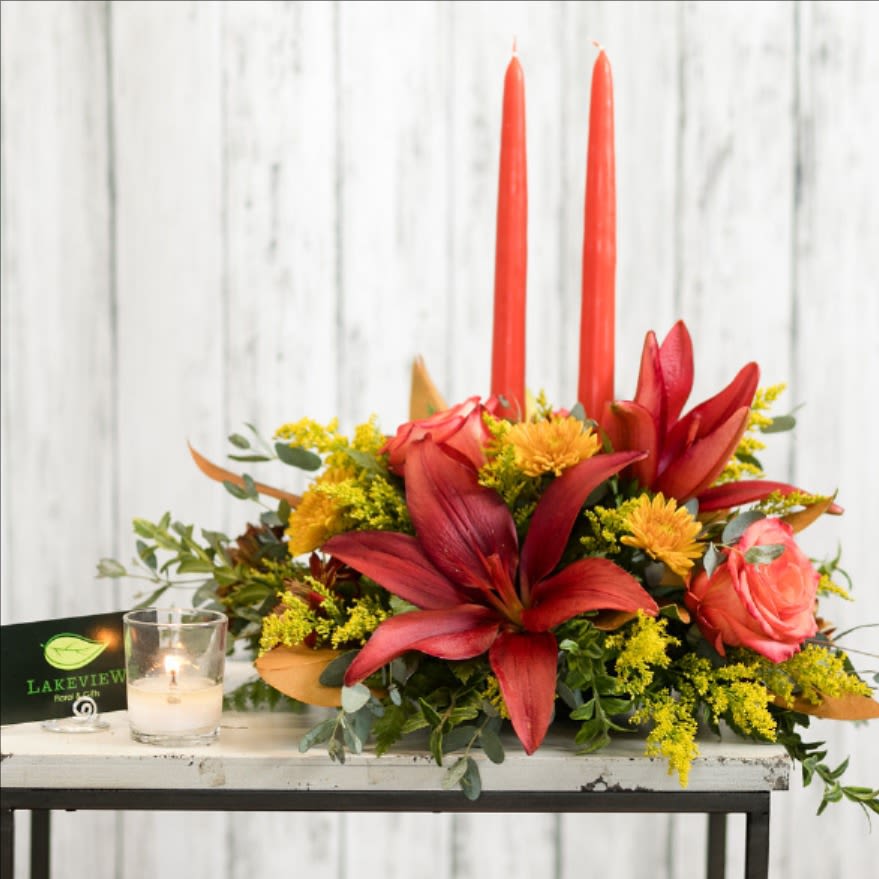 Red lilies and pink roses arranged with two tall red candles